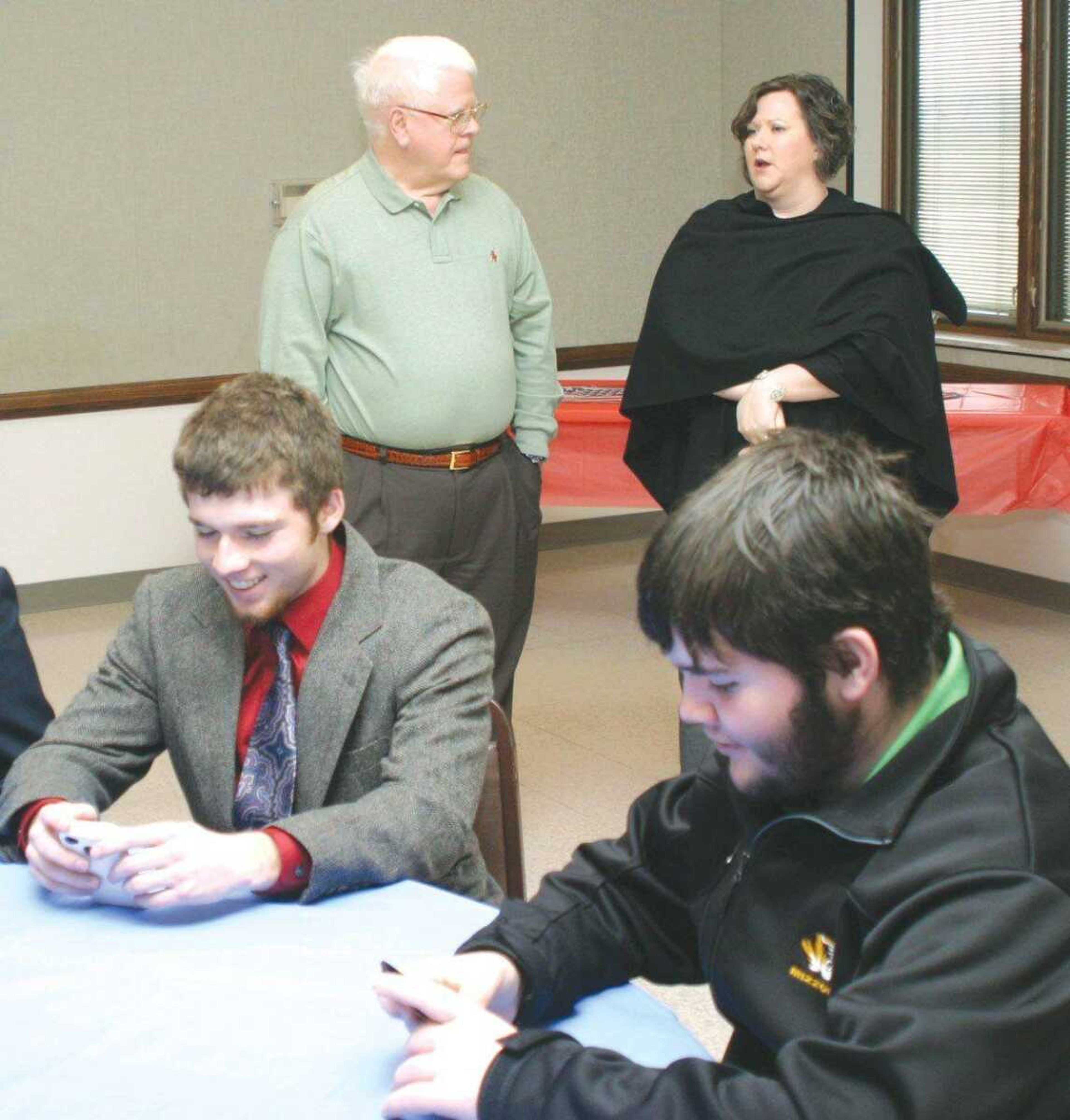 Texting while waiting for lunch to be served is a good way to pass the time. Texting while waiting at a red light? Only if you can manage it without getting pulled over, participants in Youth in Government Day's mock city council decided. Pictured from left are participants Dylan Smith and Jakob Owens, juniors at Sikeston Senior High School. Pictured in the background are Sikeston City Councilman Bob Depro and Crystie Ressel who, along with Sarah McGill, was a Sikeston Senior High School sponsor. (Scott Welton ~ Sikeston Standard Democrat)