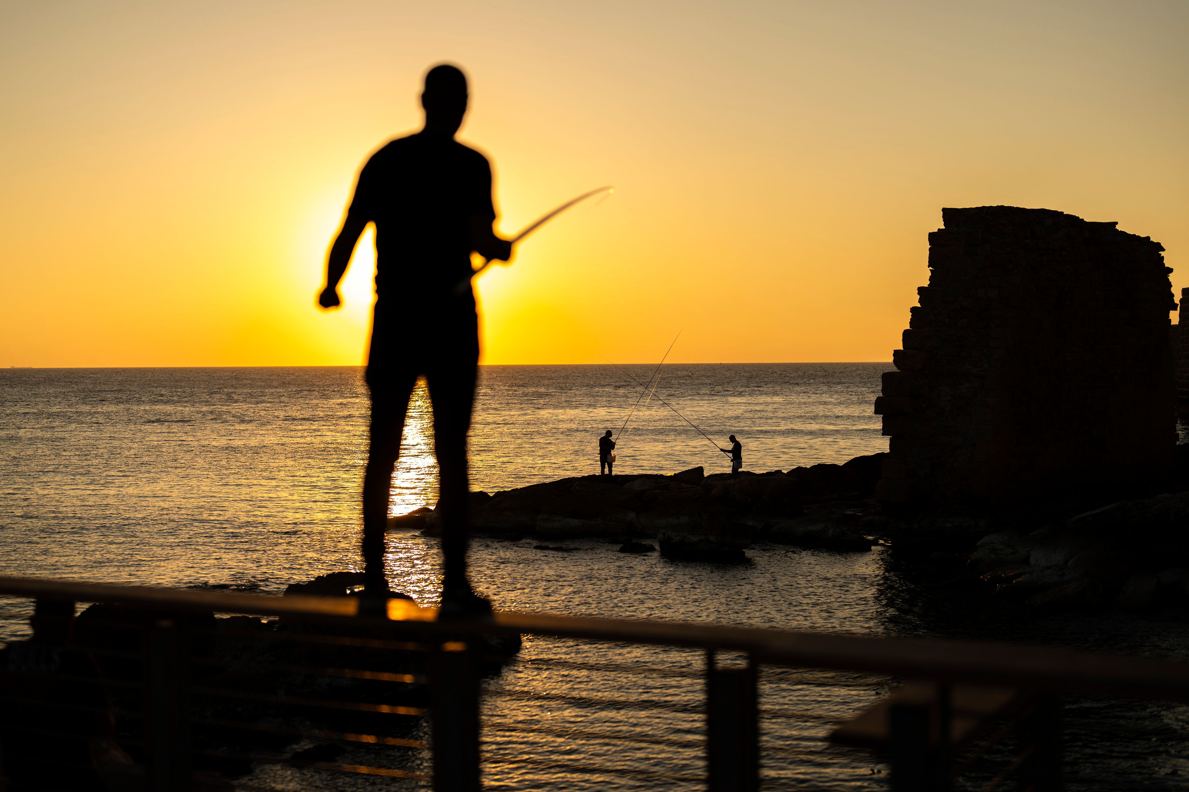 Fishermen throw their lines into the Mediterranean sea as the sun sets in the old city of Acre, Israel, on Friday, Nov. 15, 2024. (AP Photo/Francisco Seco)