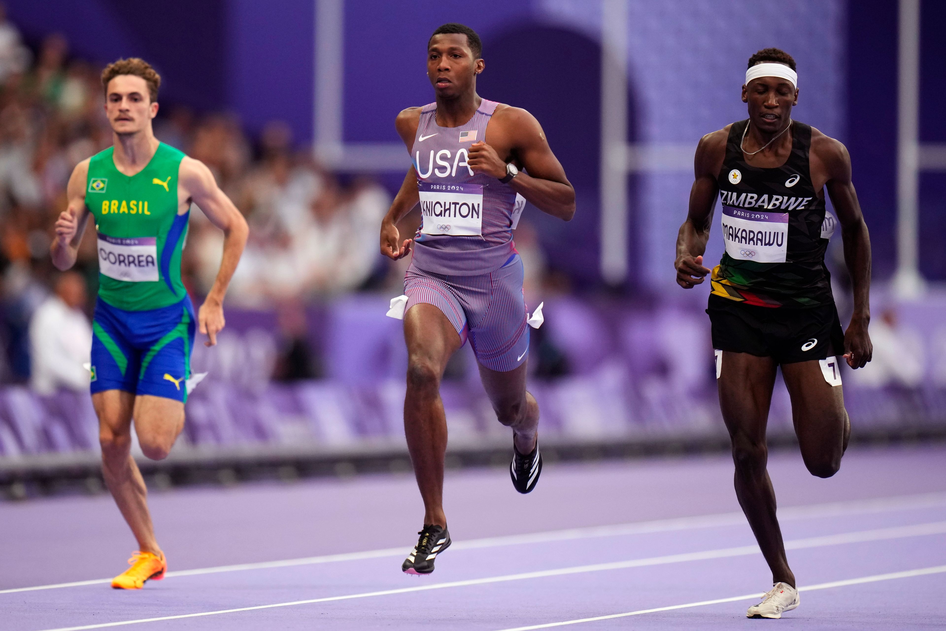 Erriyon Knighton, centre, of the United States, leads Renan Correa, left, of Brazil, and Tapiwanashe Makarawu, of Zimbabwe, compete in their men's 200-meter semifinal at the 2024 Summer Olympics, Wednesday, Aug. 7, 2024, in Saint-Denis, France. (AP Photo/Petr David Josek)