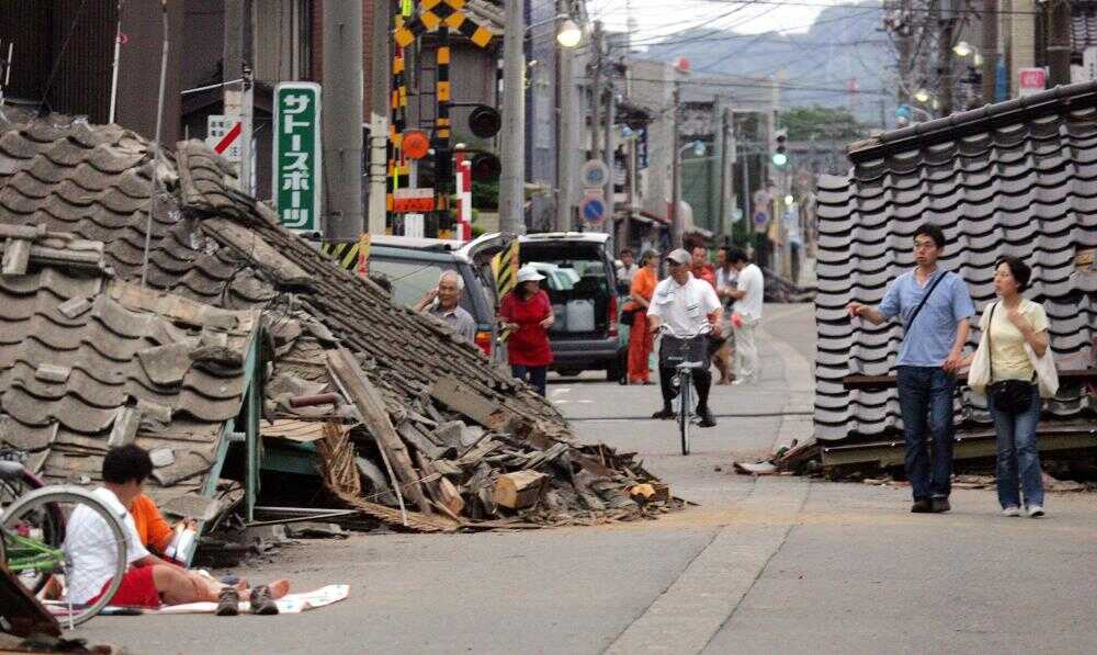 People looked at a destroyed house Monday in Kashiwazaki, Japan. A 6.8-magnitude earthquake rocked Japan's northwest coast Monday, killing at least eight people. (Koji Sasahara ~ Associated Press)