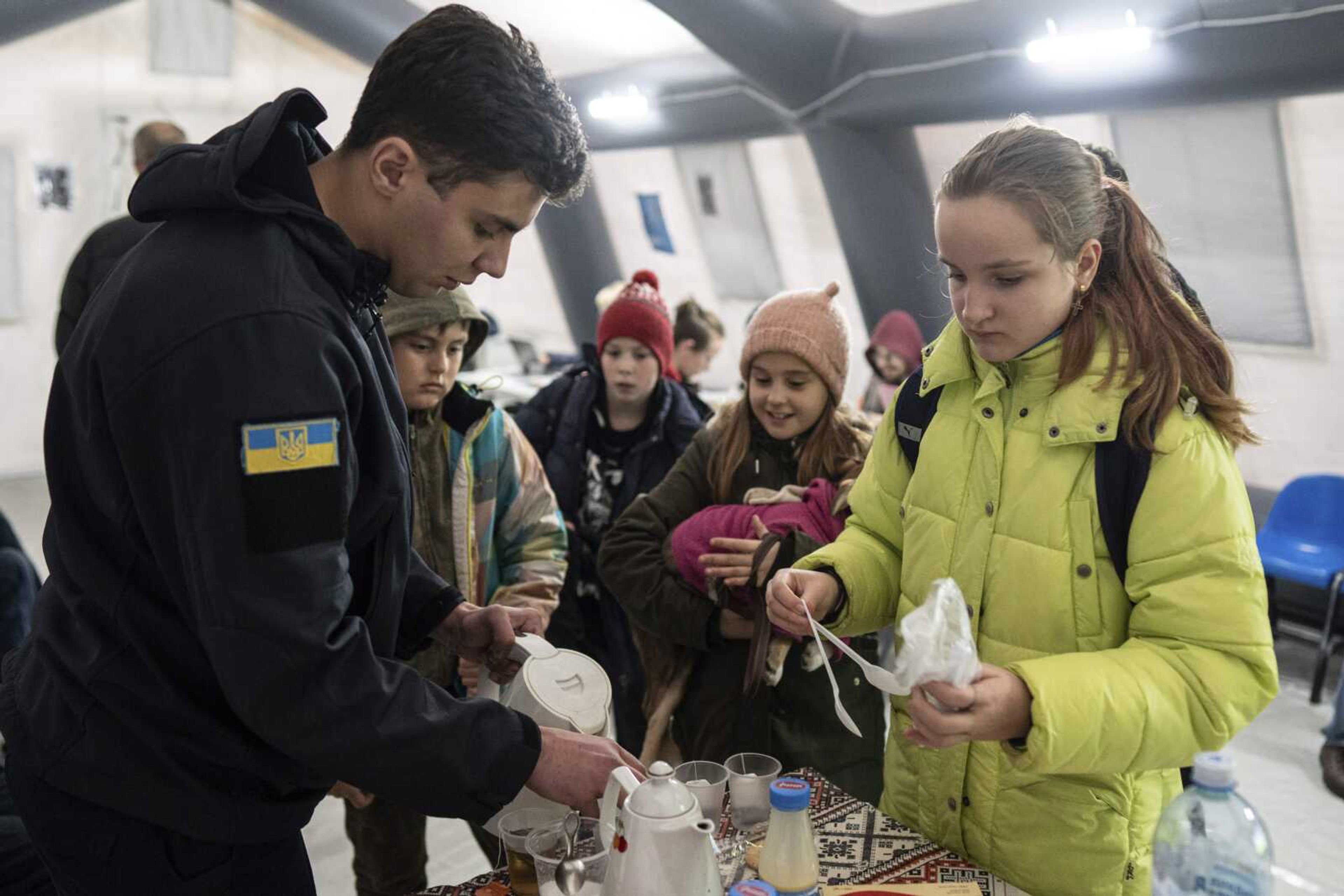 A rescue worker makes tea for children at the heating tent "Point of Invincibly" on Monday, Nov. 28, in Bucha, Ukraine.