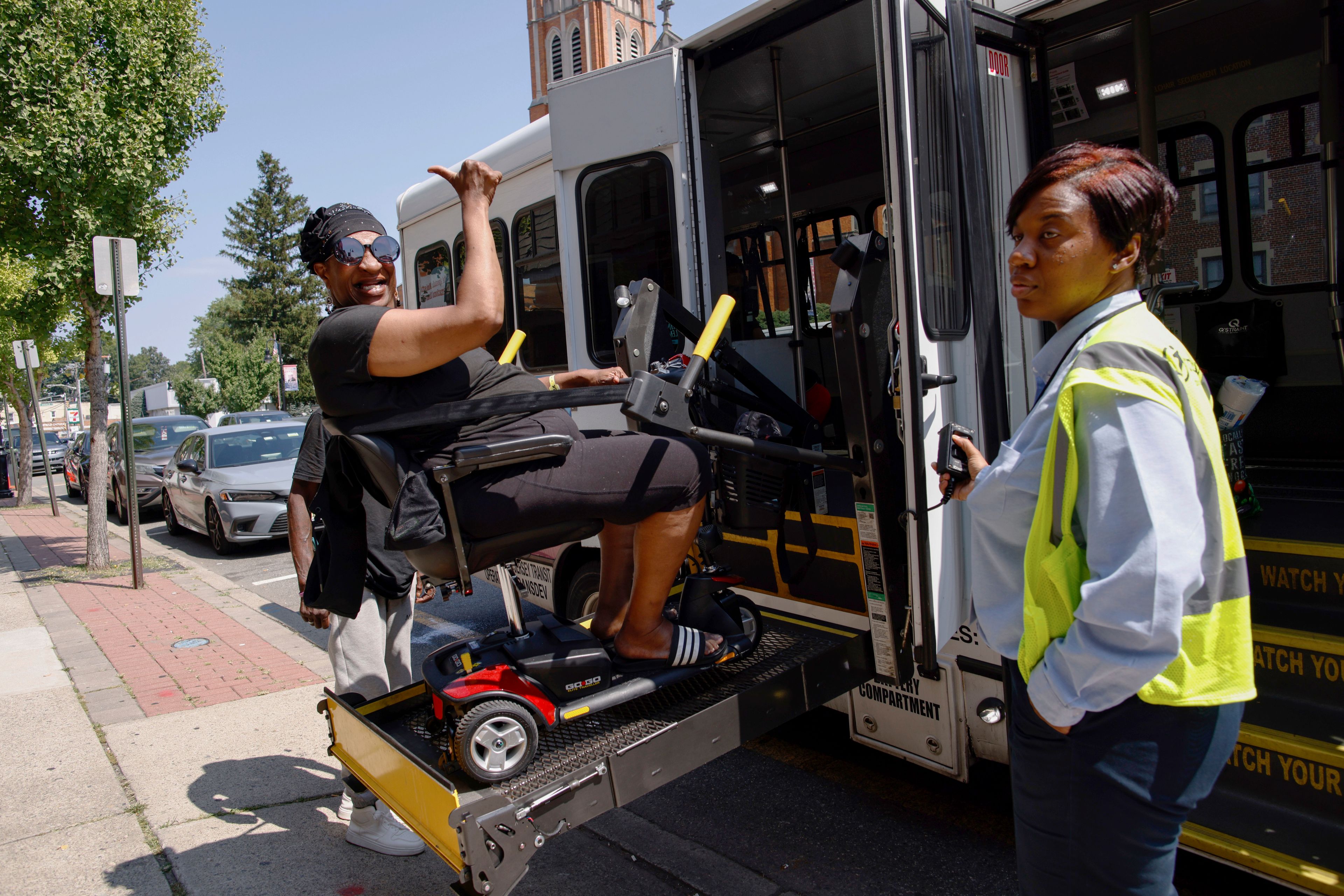 A woman waves as she boards a bus to go home, outside of Sunshine Adult Day Center in Bergenfield, N.J., Monday, Aug. 26, 2024. (AP Photo/Kena Betancur)