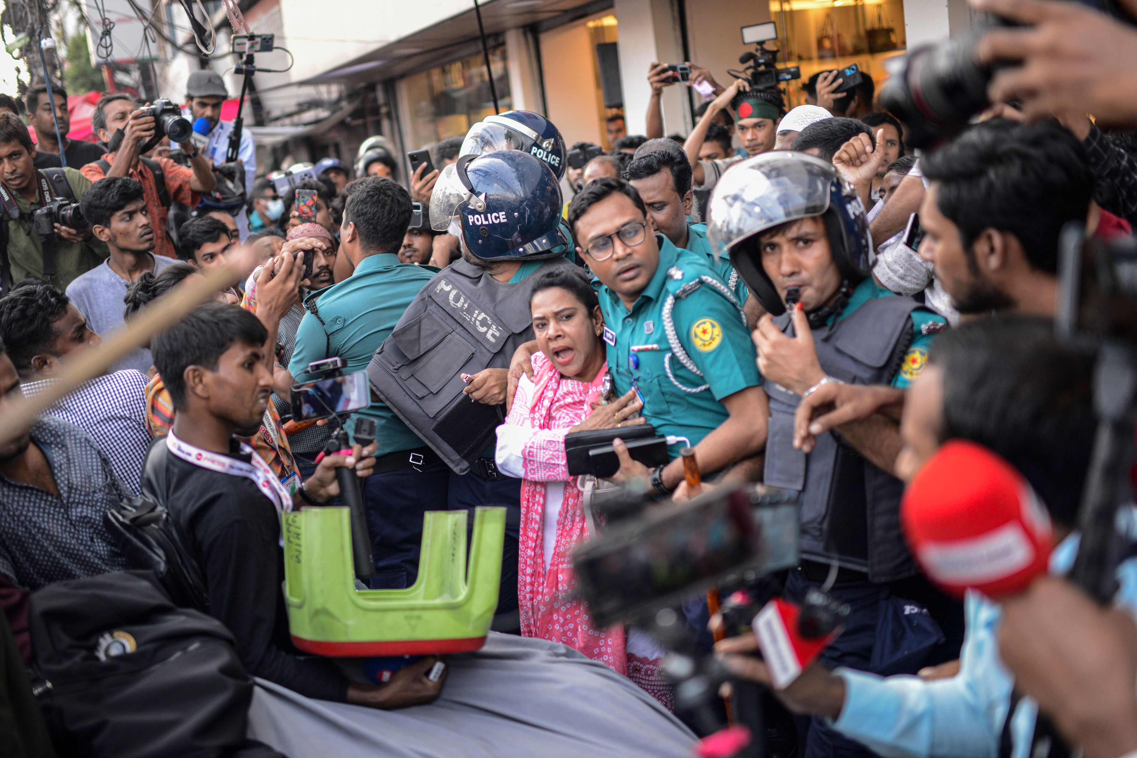 A police officer shields an Awami League woman supporter from students from anti-discrimination movements in Dhaka, Bangladesh, Sunday, Nov. 10, 2024. (AP Photo/Mahmud Hossain Opu)