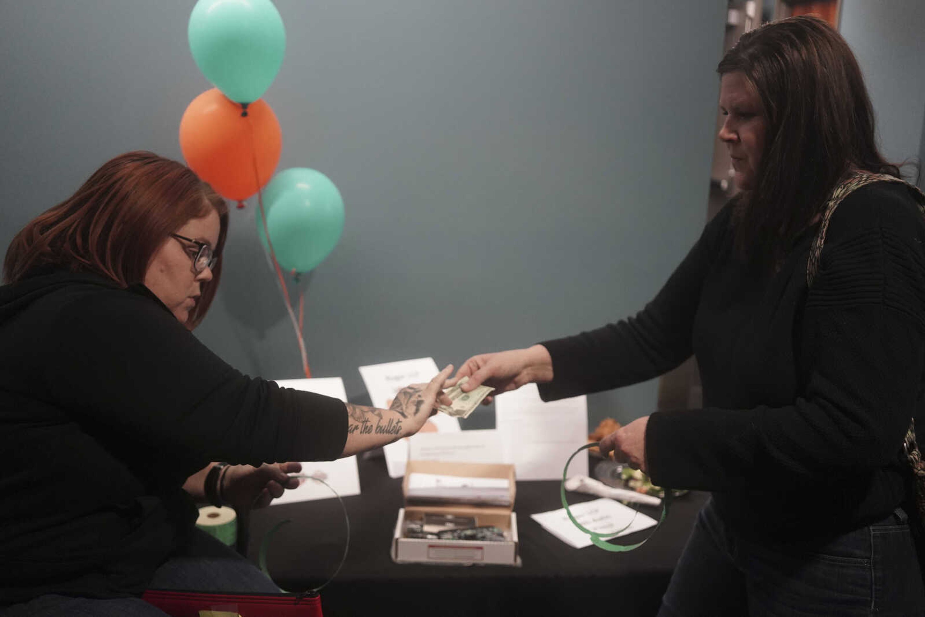 Jennifer Sokolowski, right, purchases raffle tickets in the hopes of winning a pistol from Falynne Muzzy, left, during the Humane Society of Southeast Missouri Power of Pawsitivity fundraiser Saturday, Feb. 29, 2020, at the Jackson Civic Center in Jackson.