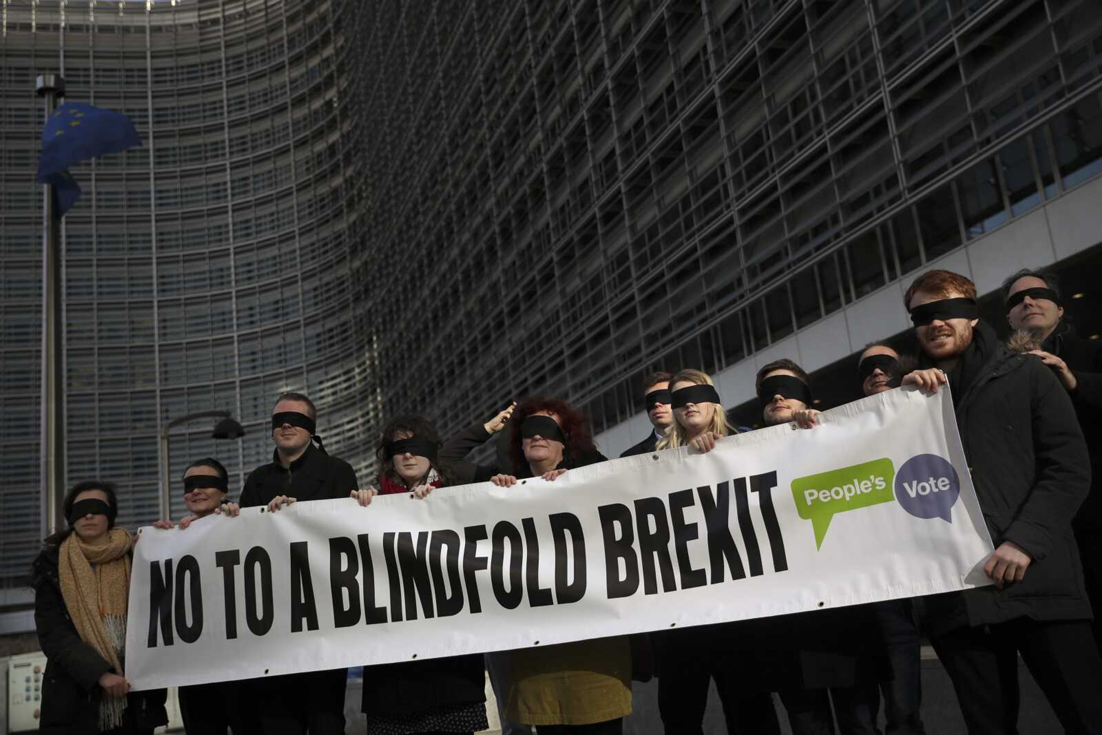 Blindfolded protesters against Brexit hold a banner Thursday outside the European Commission headquarters during a meeting between European Commission President Jean-Claude Juncker and British Prime Minister Theresa May in Brussels.