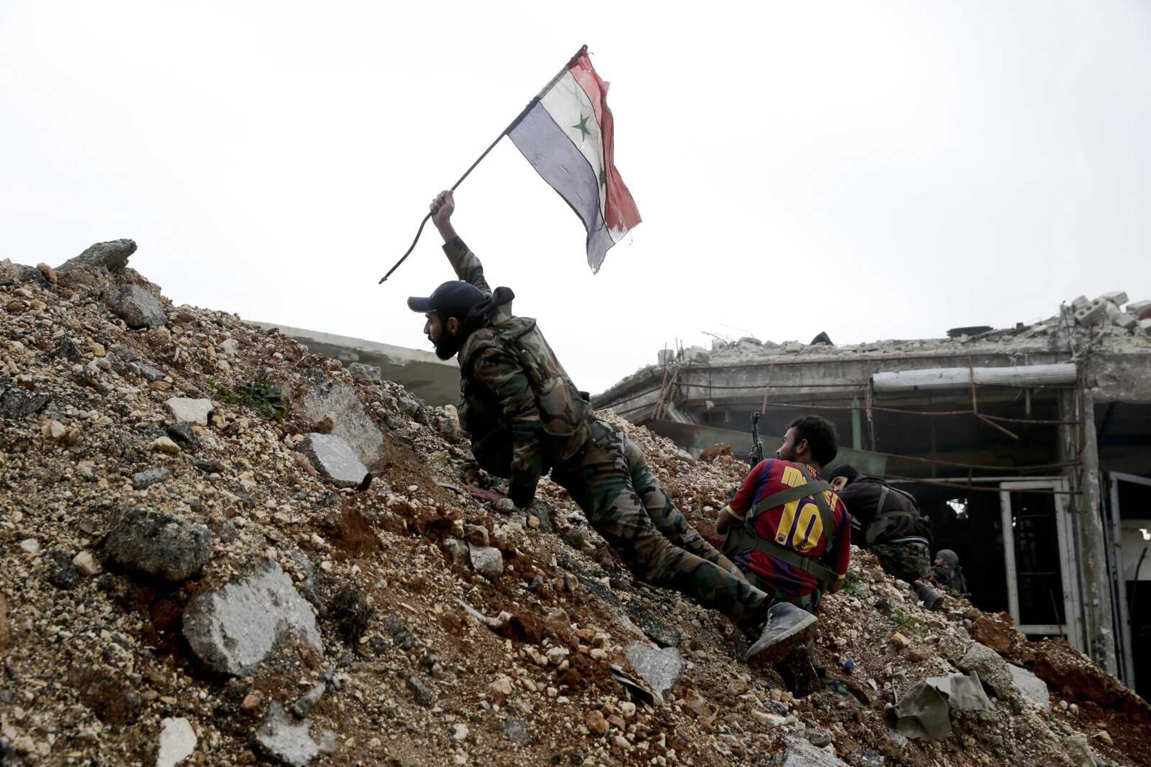 A Syrian army soldier places a Syrian national flag during a battle Monday with rebel fighters at the Ramouseh front line, east of Aleppo, Syria. The government seized large swathes of the Aleppo enclave under rebel control since 2012 in the offensive that began last week. The fighting was most intense Monday near the dividing line between east and west Aleppo as government and allied troops push their way from the eastern flank, reaching within less than a kilometer (half a mile) from the citadel that anchors the center of the city. (AP Photo/Hassan Ammar)