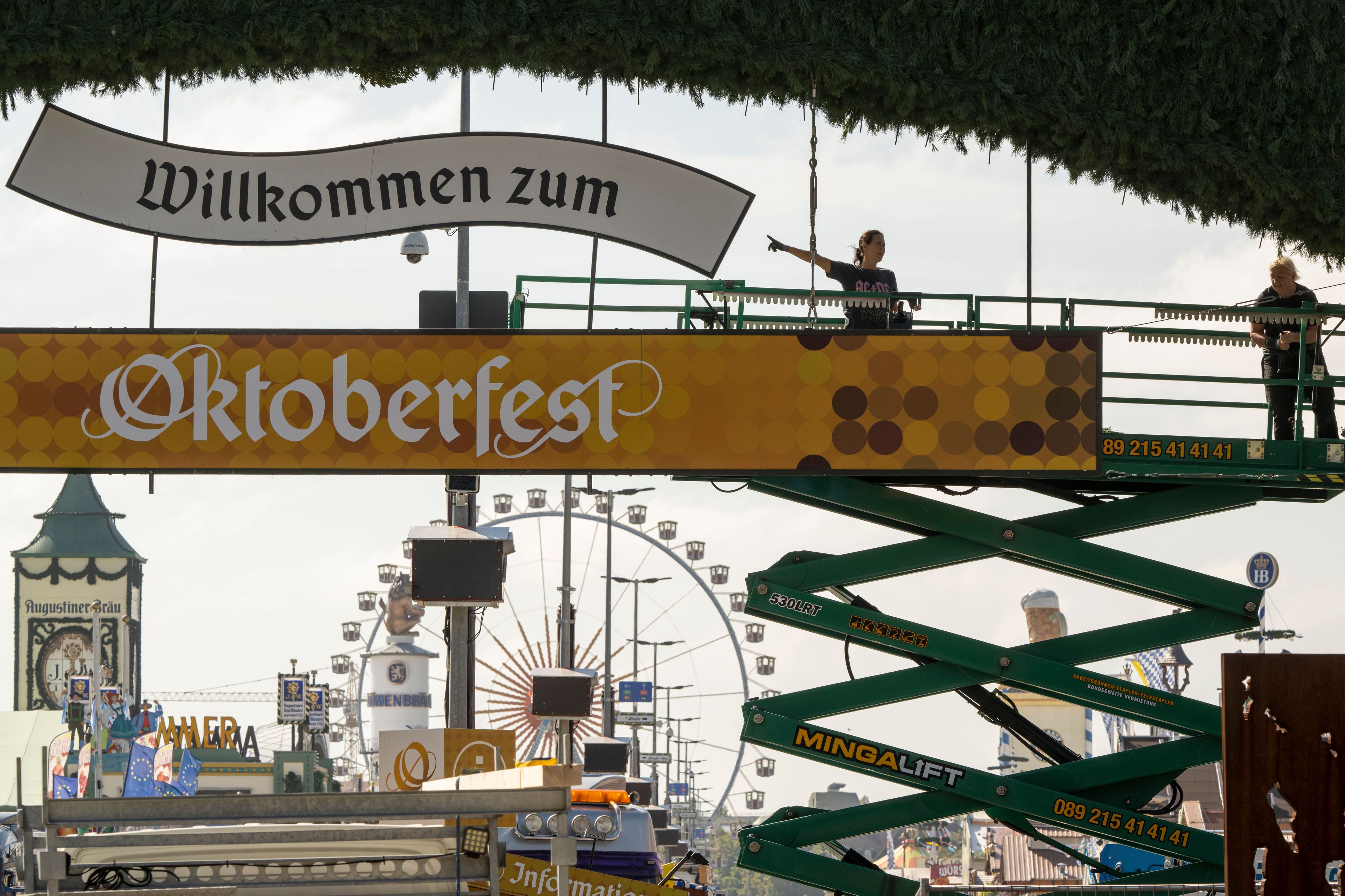 Workers stand on a lifting platform during construction work on the Oktoberfest grounds at the main entrance, in Munich, Germany, Wednesday, Sept. 18, 2024. (Peter Kneffel/dpa via AP)