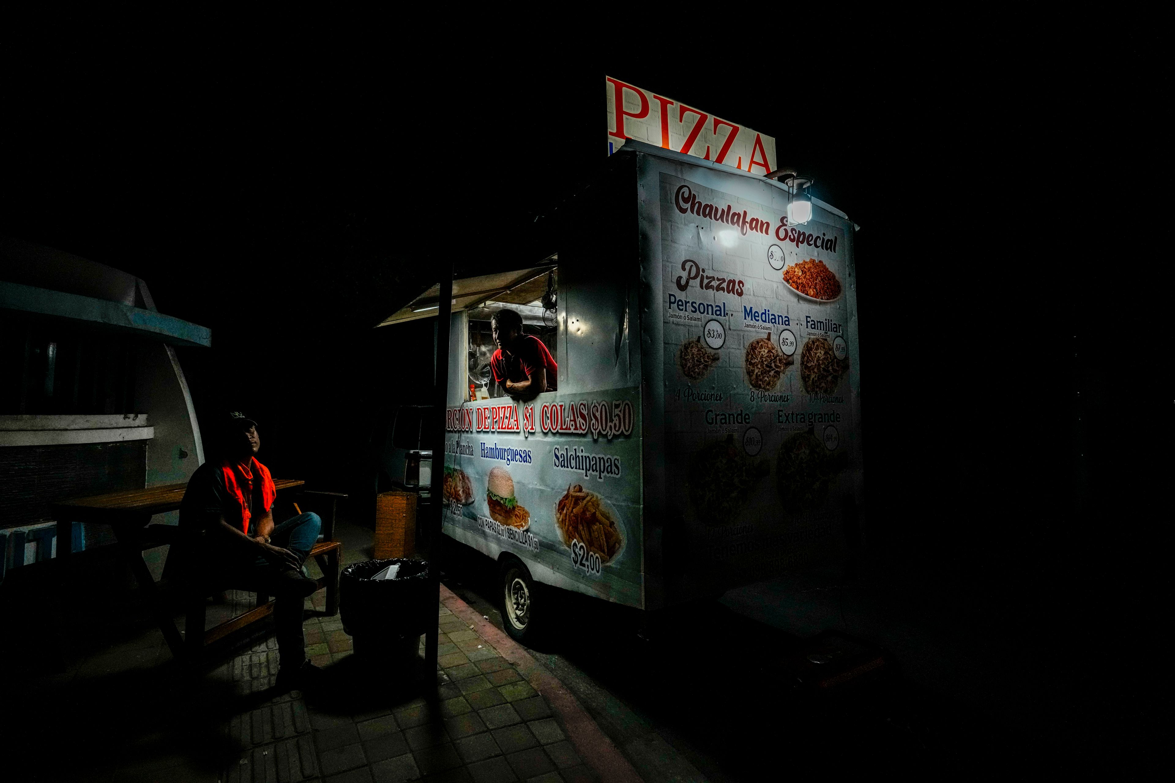 A street vendor uses a generator-powered light bulb amid rolling blackouts in Manta, Ecuador, Sept. 23, 2024. (AP Photo/Dolores Ochoa)