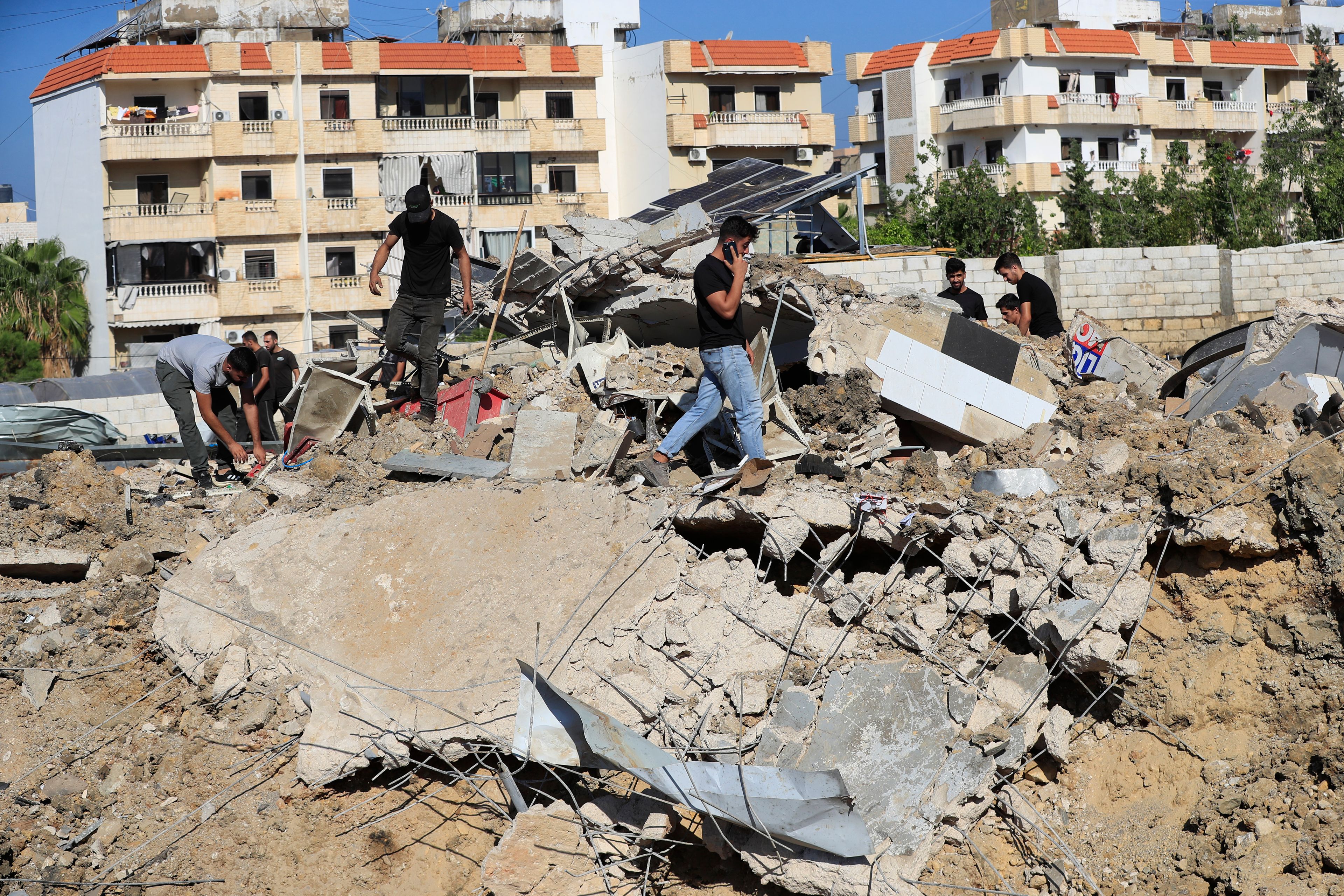 People gather at the site of an Israeli airstrike that hit a hangar in the southern town of Jiyeh, Lebanon, Wednesday, Sept. 25, 2024. (AP Photo/Mohammed Zaatari)