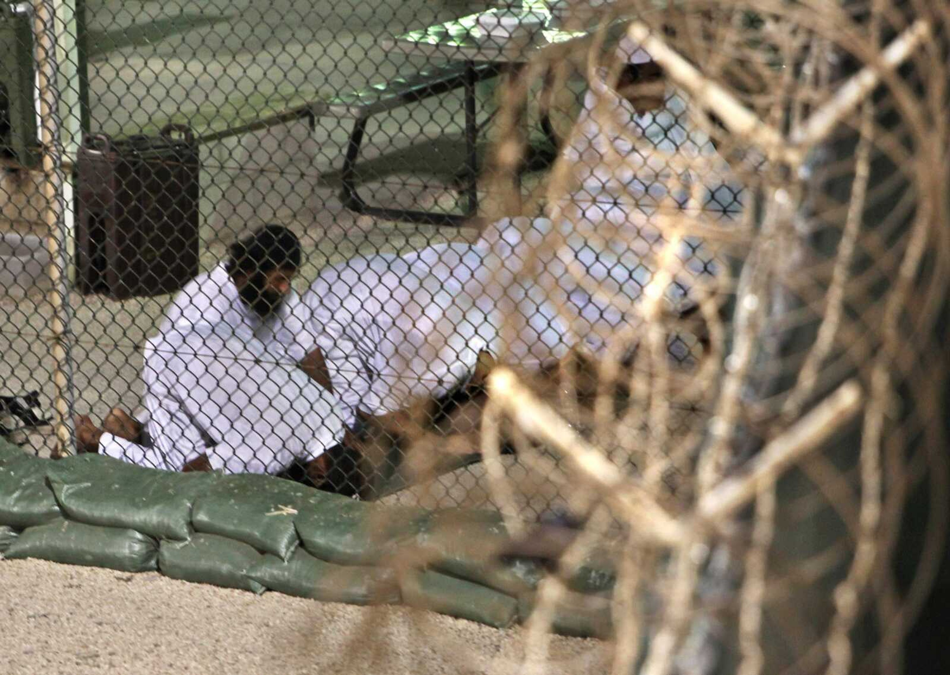 In this photo reviewed by the U.S. military, Guantanamo detainees pray before dawn May 14 near a fence of razor-wire inside the exercise yard at Camp 4 detention facility at Guantanamo Bay U.S. Naval Base, Cuba. (Associated Press)