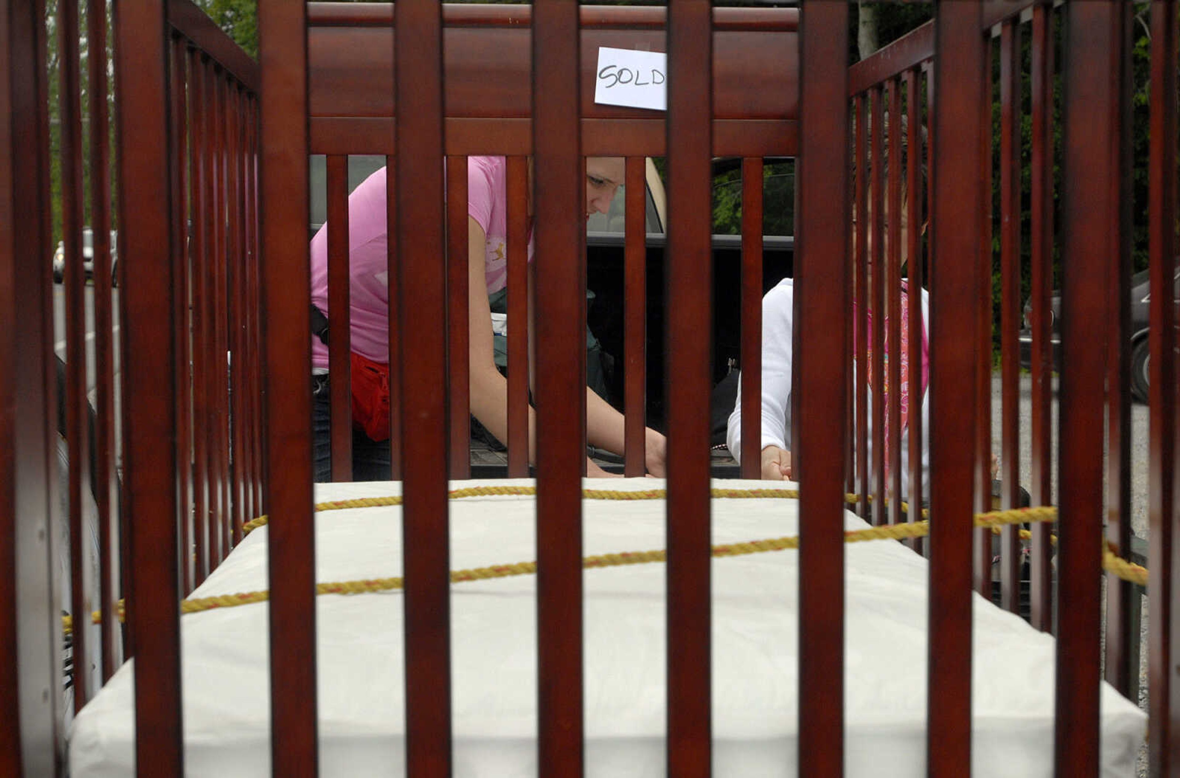 LAURA SIMON~lsimon@semissourian.com
Julie Bruckner, left, and Michelle Schwalbert tie down a baby crib their friend purchased Friday, May 27, 2011 in Dutchtown during the 100-Mile Yard sale.