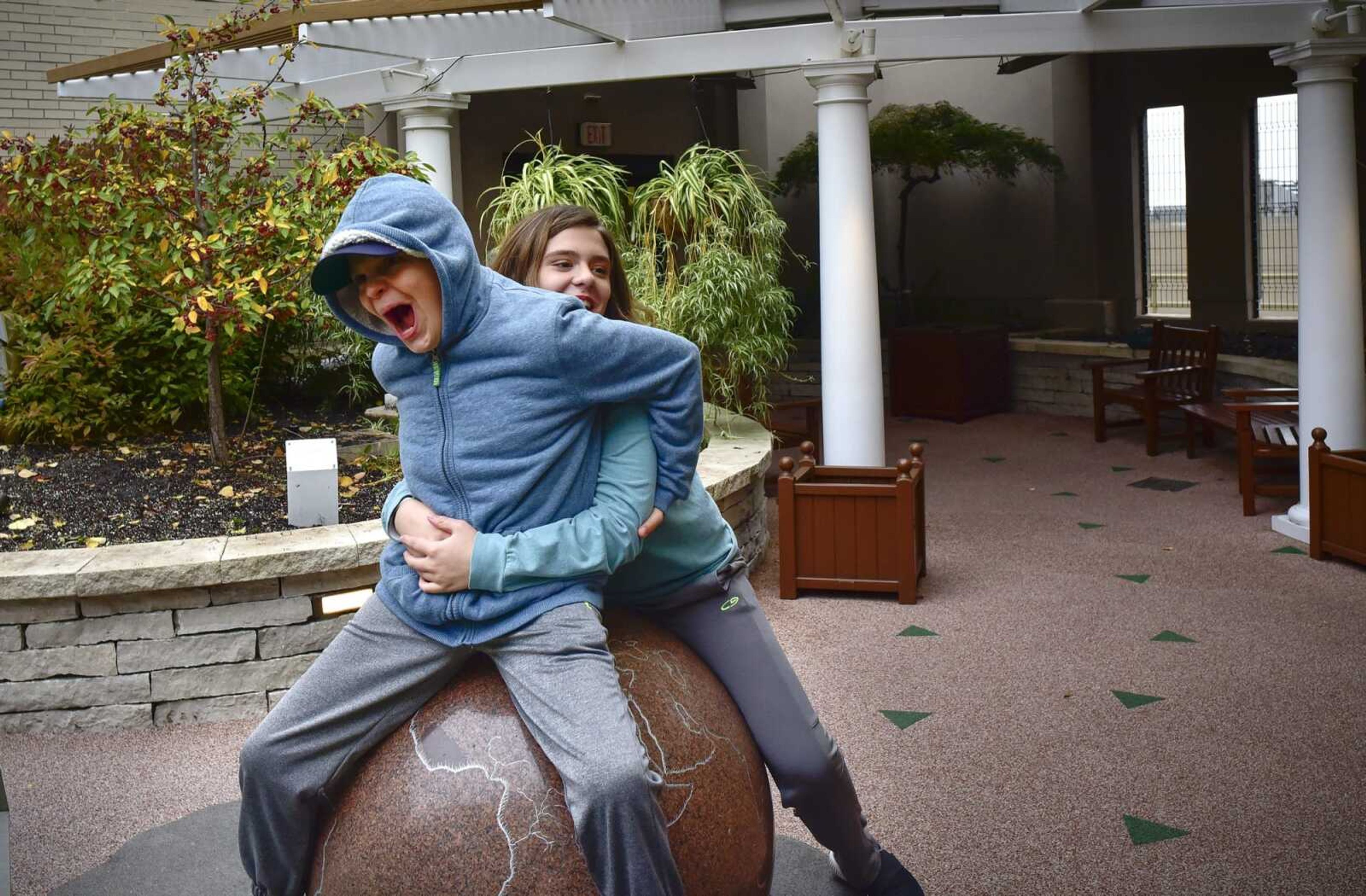 Cape Girardeau twins Matthew and Allee McKee wrestle in The Olson Family Garden during a day of medical appointments Oct. 29 at St. Louis Children's Hospital.