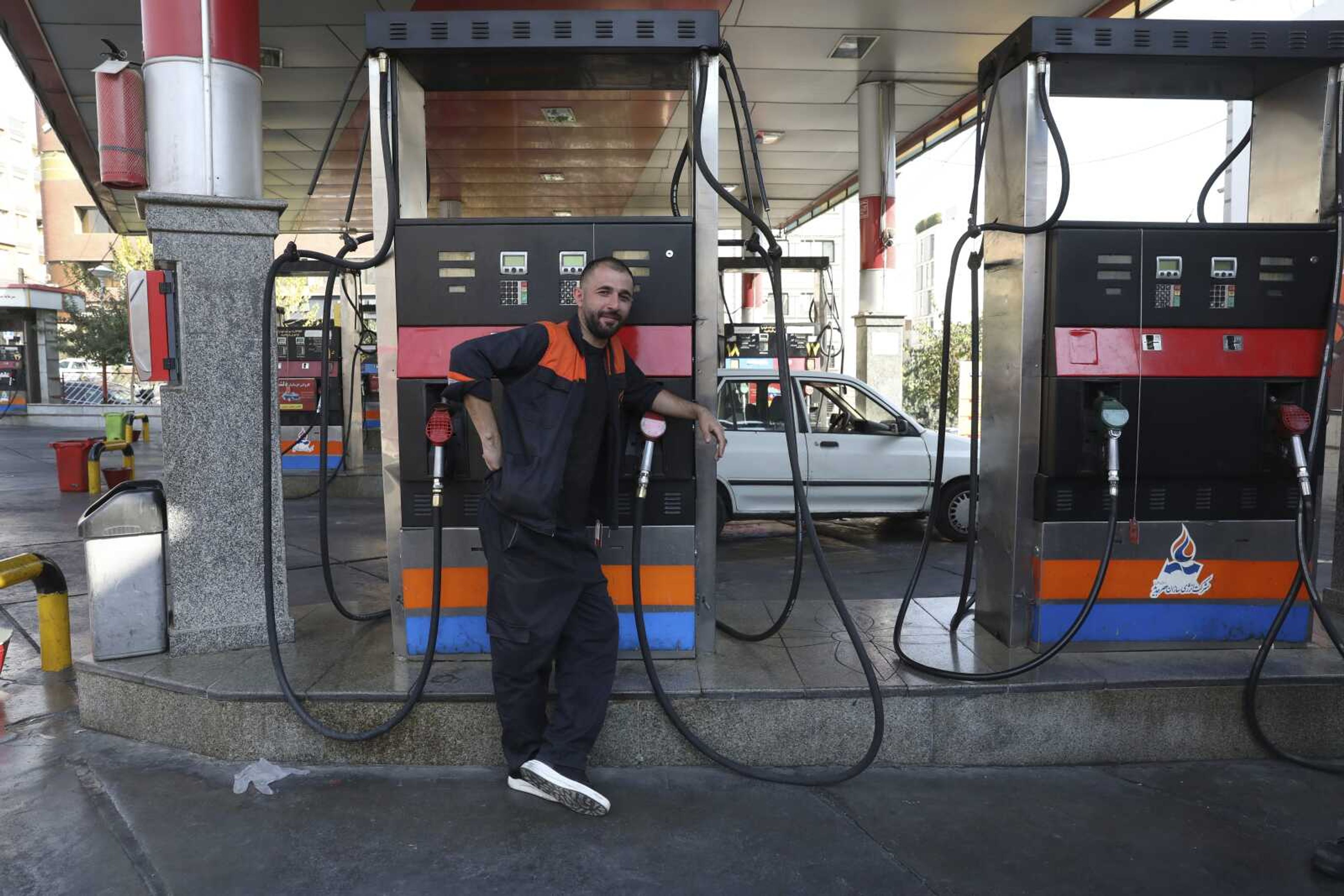 A worker leans against a gasoline pump that has been turned off Tuesday at a gas station in Tehran, Iran.