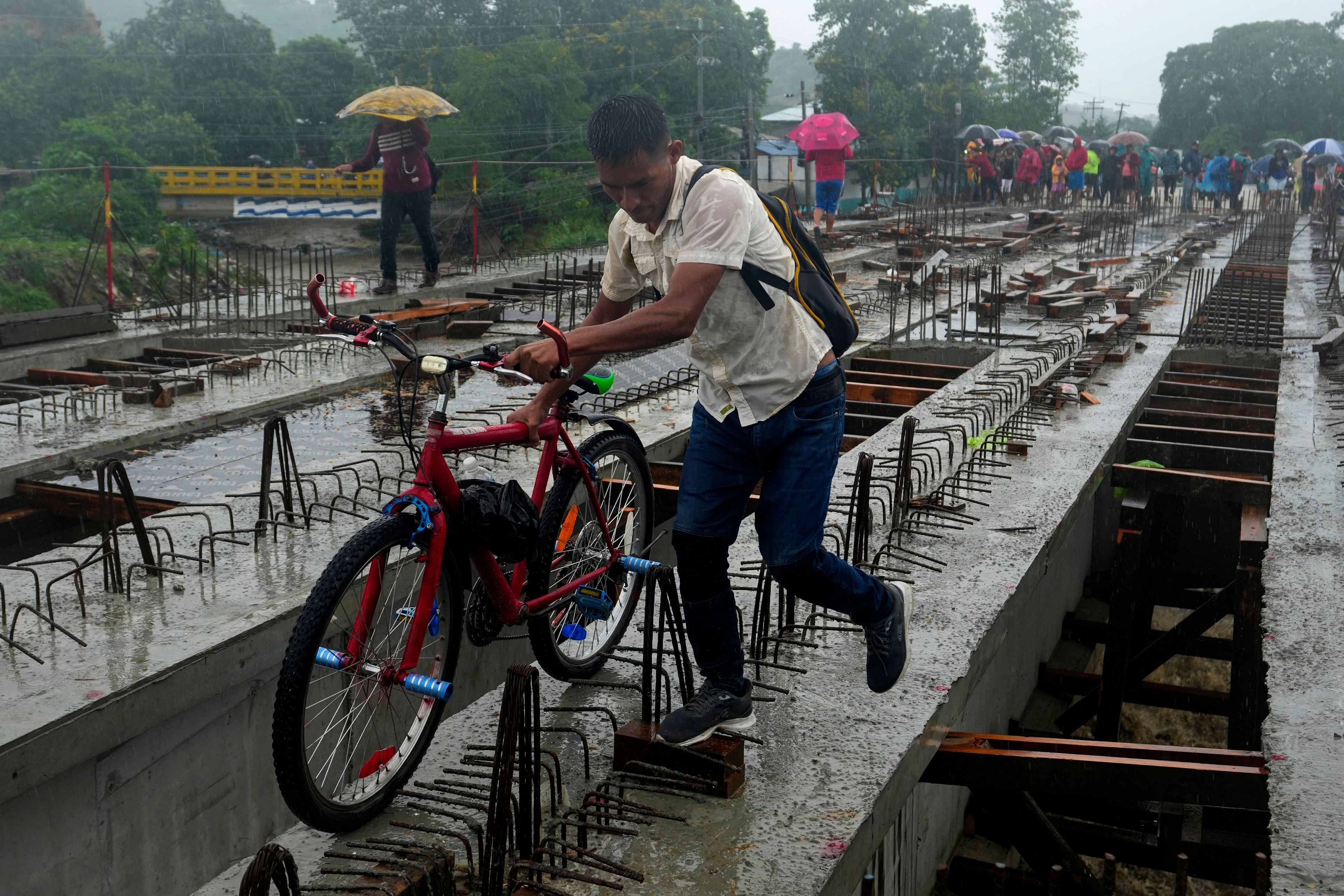 Residents cross a bridge under construction amid rain showers brought on by Tropical Storm Sara, on the outskirts of San Pedro Sula, Honduras, Nov. 16, 2024. (AP Photo/Moises Castillo)