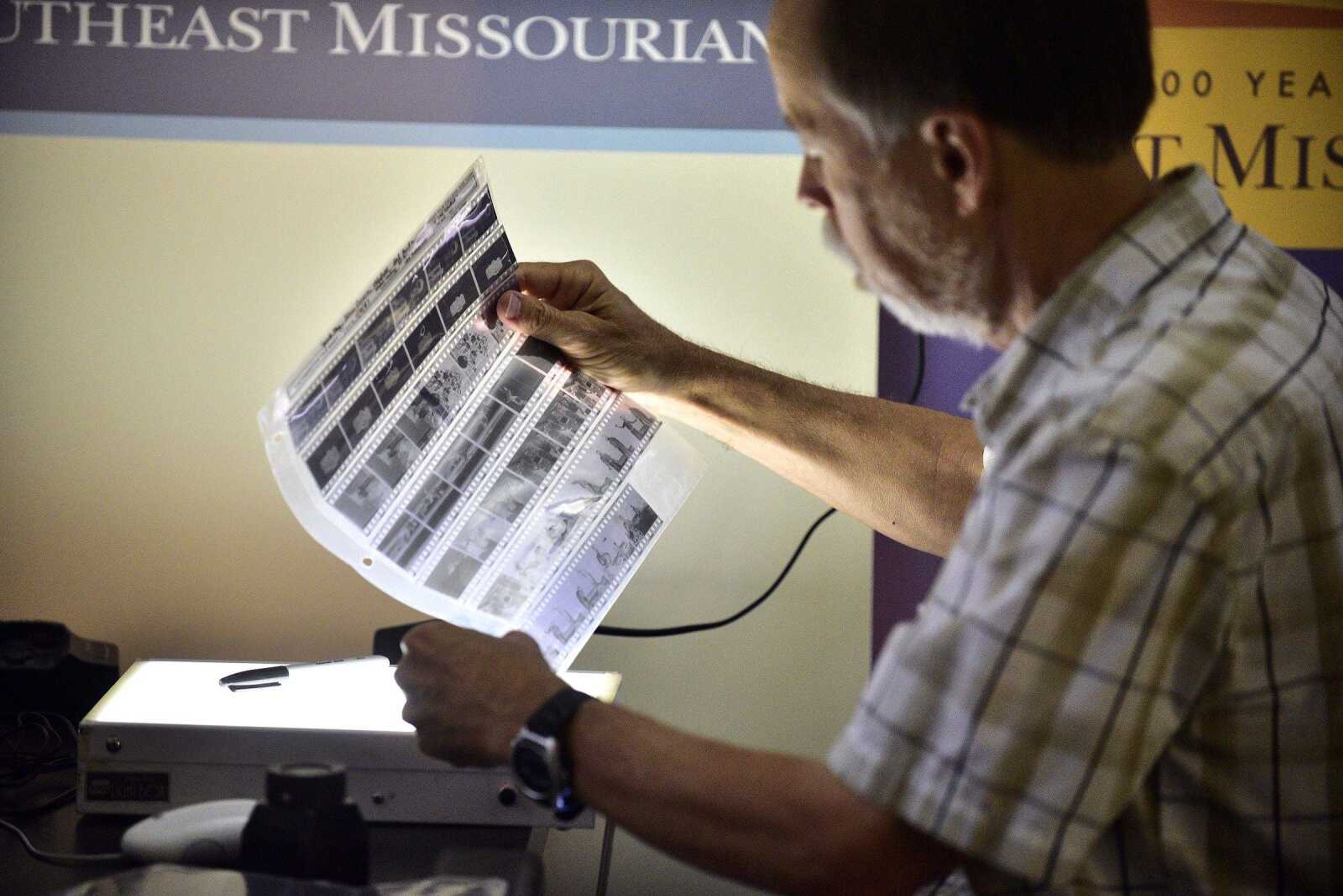 Southeast Missourian photojournalist, Fred Lynch, looks through a sleeve of old black and white negatives in the photo office on Friday, June 9, 2017.