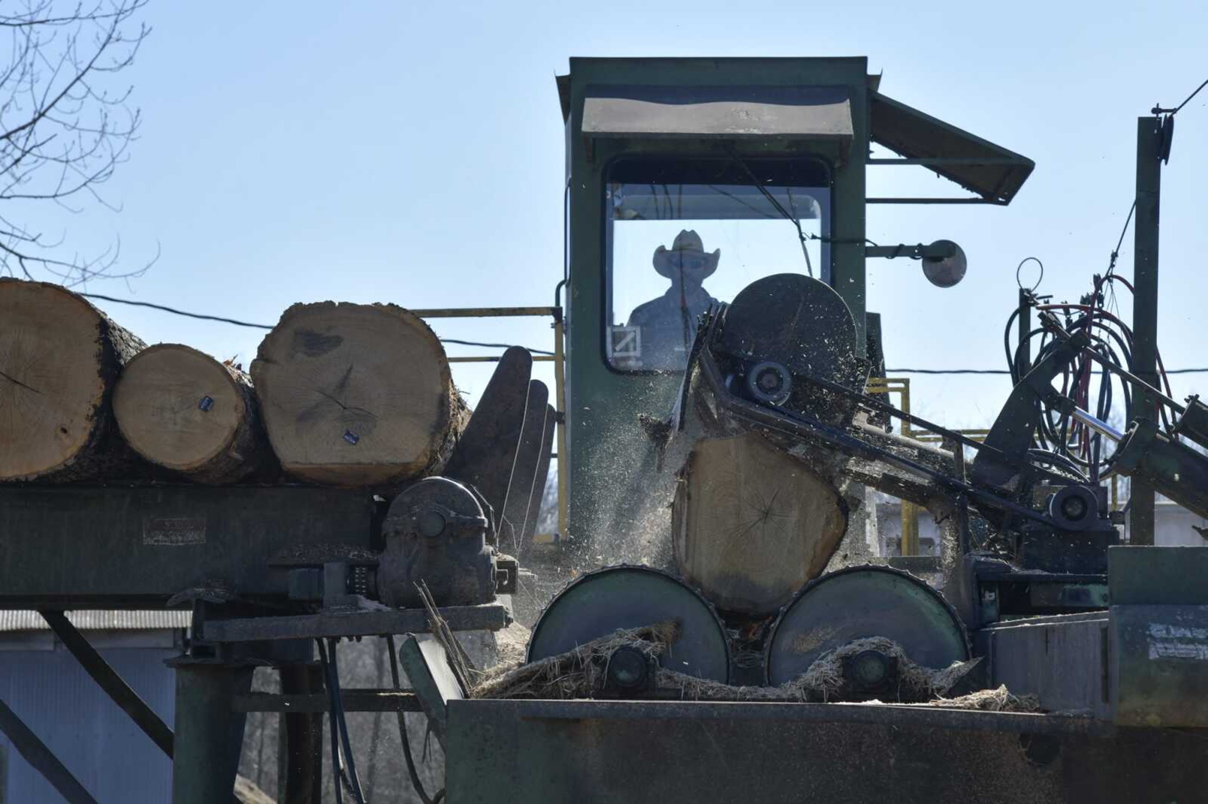 An employee operates a "de-barking" machine, which removes bark from American white oak logs bought by the Perryville Stave Co., on Thursday in Perryville, Missouri.