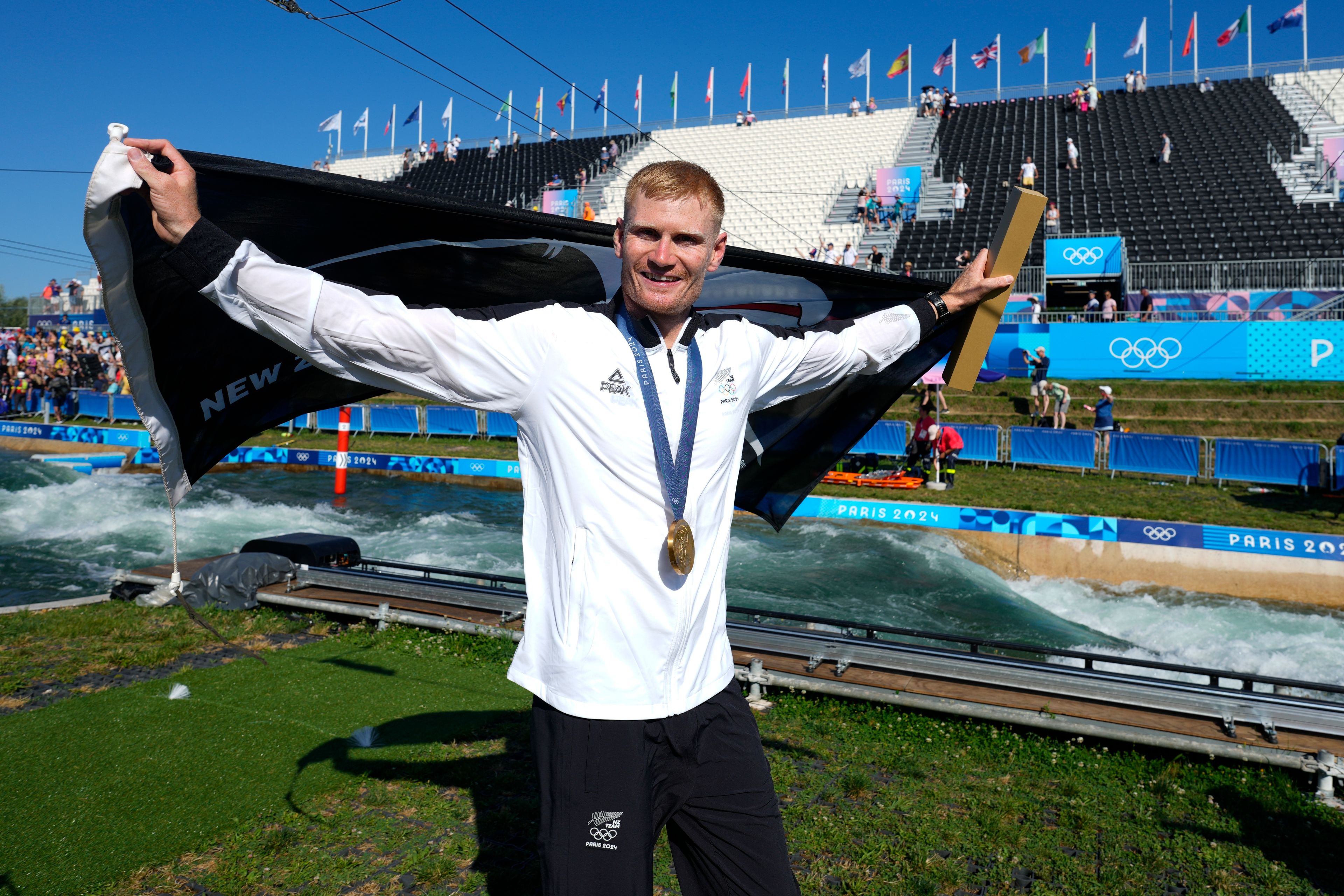 Finn Butcher of New Zealand celebrates his gold medal in the men's kayak cross finals during the canoe slalom at the 2024 Summer Olympics, Monday, Aug. 5, 2024, in Vaires-sur-Marne, France. (AP Photo/Kirsty Wigglesworth)