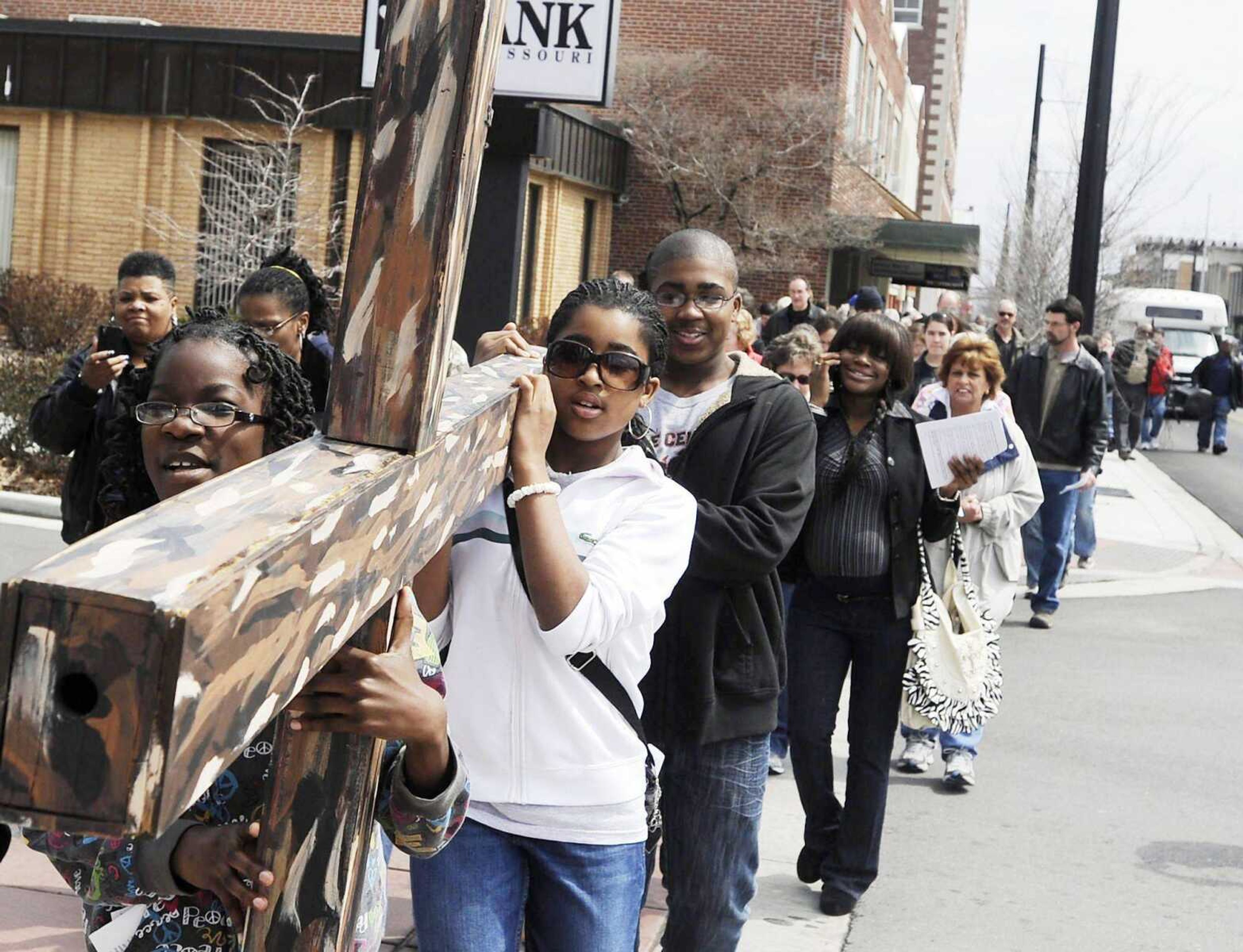 Tyra Johnson, left, Ta&#8217;Brea Harris and Taveon Harris carry a cross down Broadway during the Stations of the Cross Friday, March 29, 2013, in downtown Cape Girardeau. Nearly 200 people participated in the annual event on Good Friday. The procession traveled to 14 locations for the 14 stations of the cross which represent Jesus Christ carrying the cross to his crucifixion. (Adam Vogler)