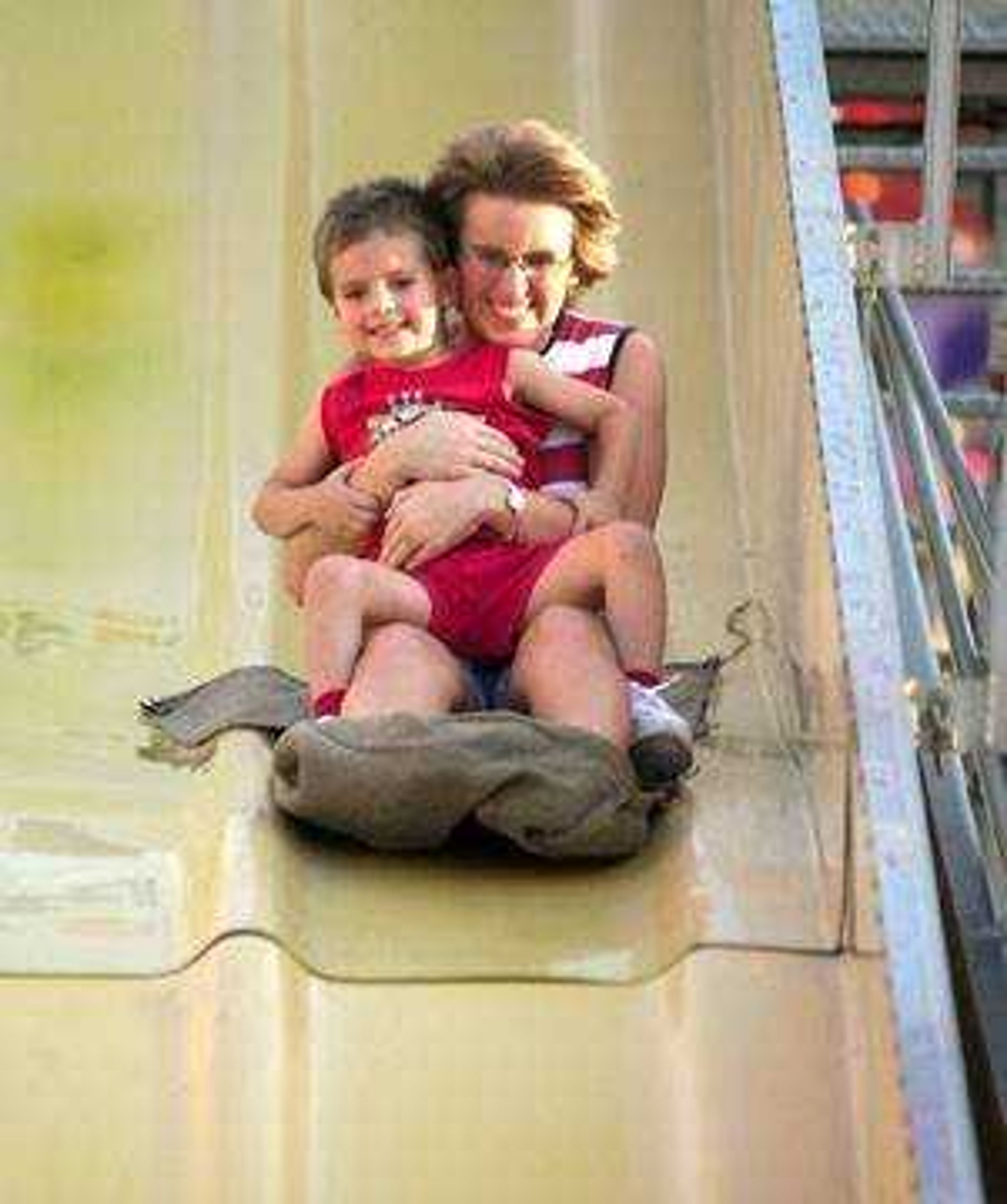 Cindy Wachter hangs on tight to her 3 year old son, Riley Wachter as they take a wild ride on the Fun Slide during Wednesday's, Jackson Homecomers.