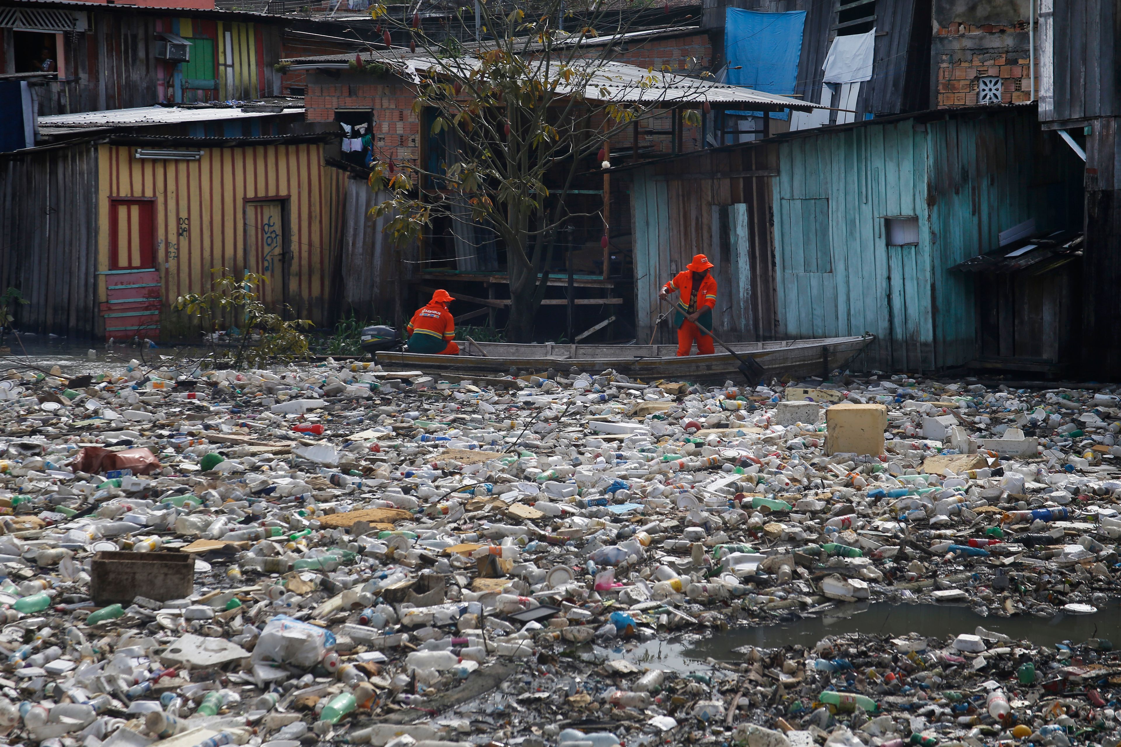 FILE - City workers remove garbage floating on the Negro River, which has a rising water level due to rain, in Manaus, Amazonas state, Brazil, June 6, 2022. (AP Photo/Edmar Barros, File)