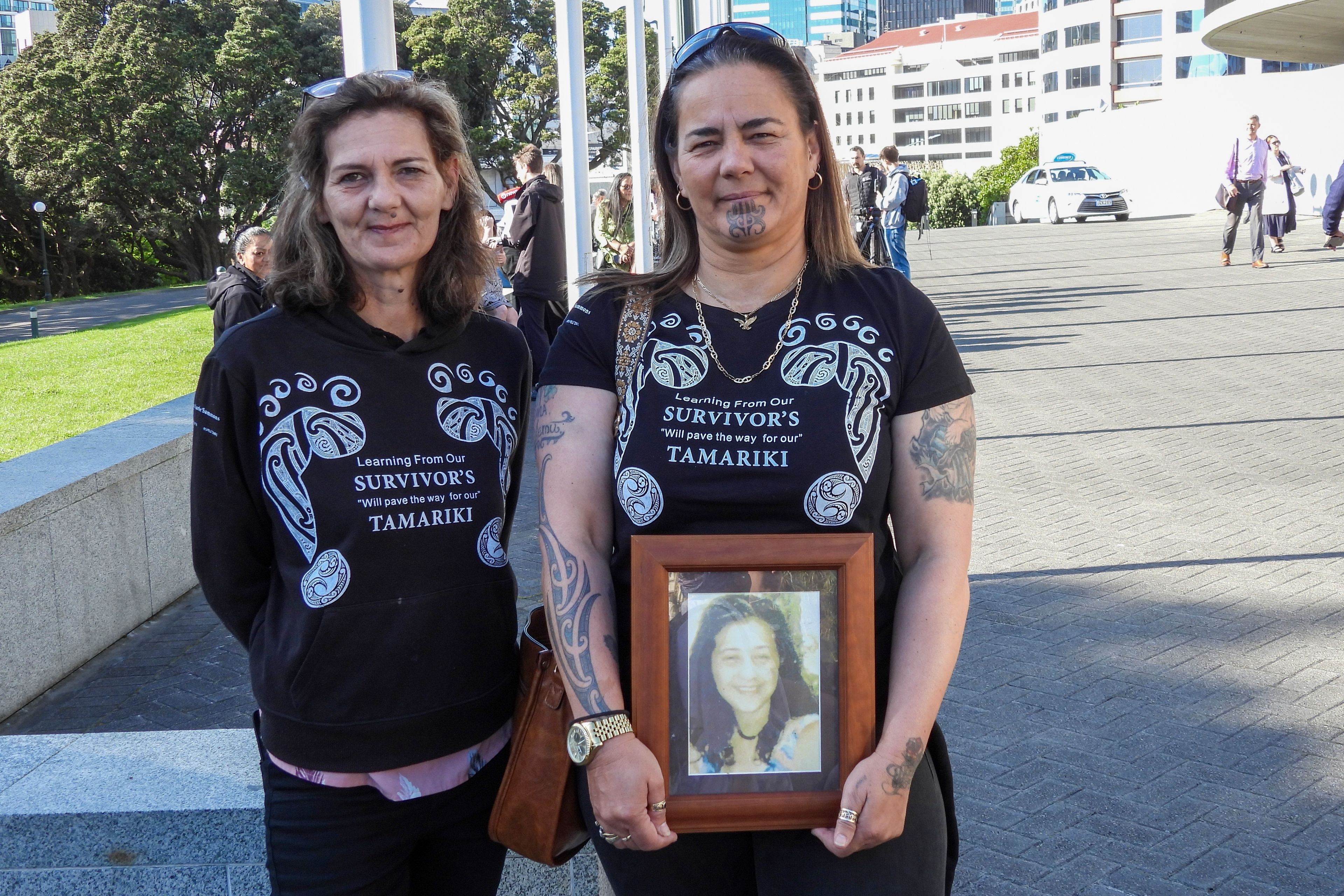 Gina, right, and Tanya Sammons hold a photo of their late sister Alva as they arrive at Parliament House in Wellington, New Zealand, ahead of the apology to the survivors of abuse in state, faith-based and foster care over a period of seven decades, Tuesday, Nov. 12, 2024. (AP Photo/Charlotte Graham-McLay )