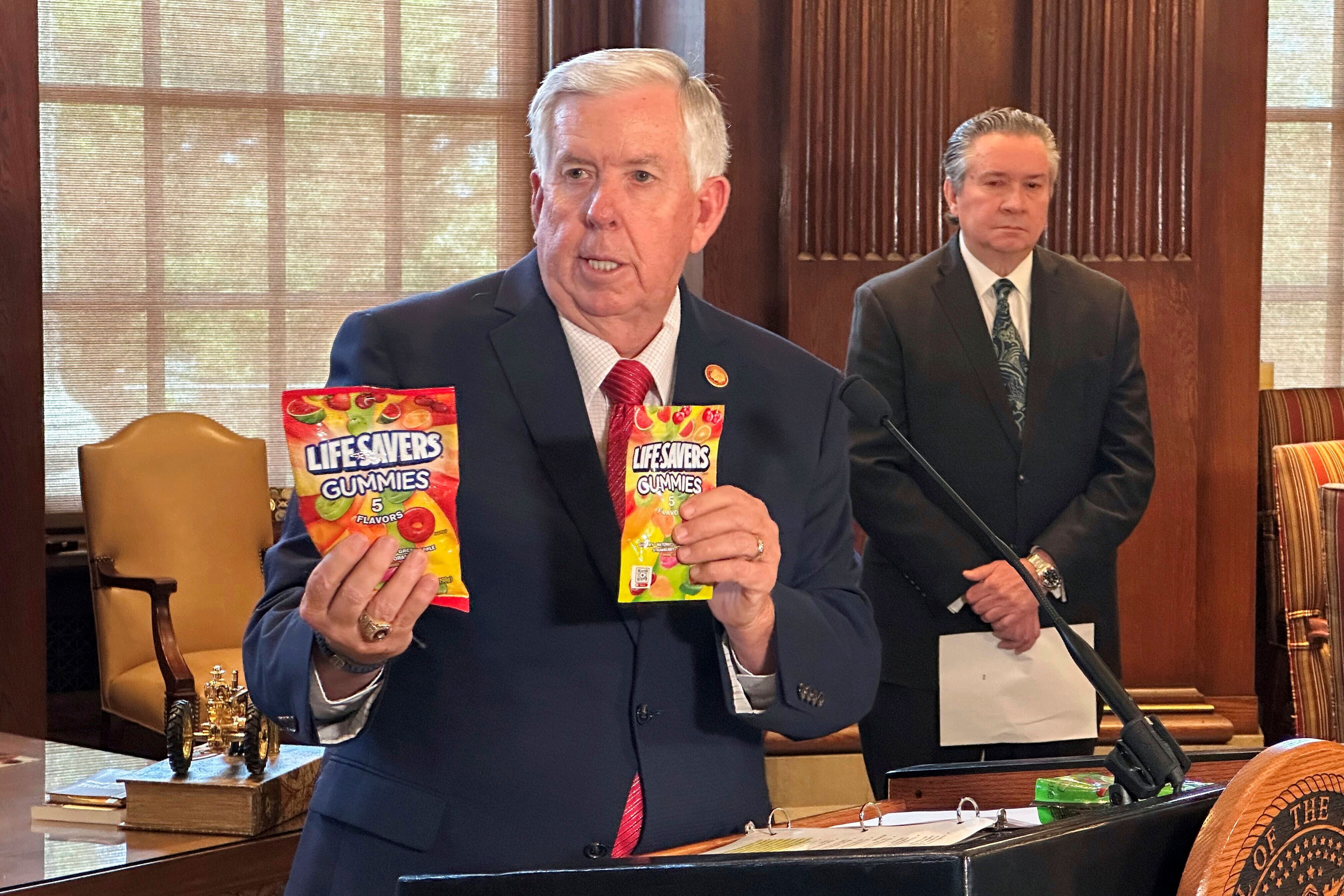 FILE - Missouri Gov. Mike Parson holds up an example of a legal package of Life Savers Gummies, left, and a slightly smaller package of hemp-derived gummies, right, at the Capitol in Jefferson City, Missouri. (AP Photo/David A. Lieb, File)