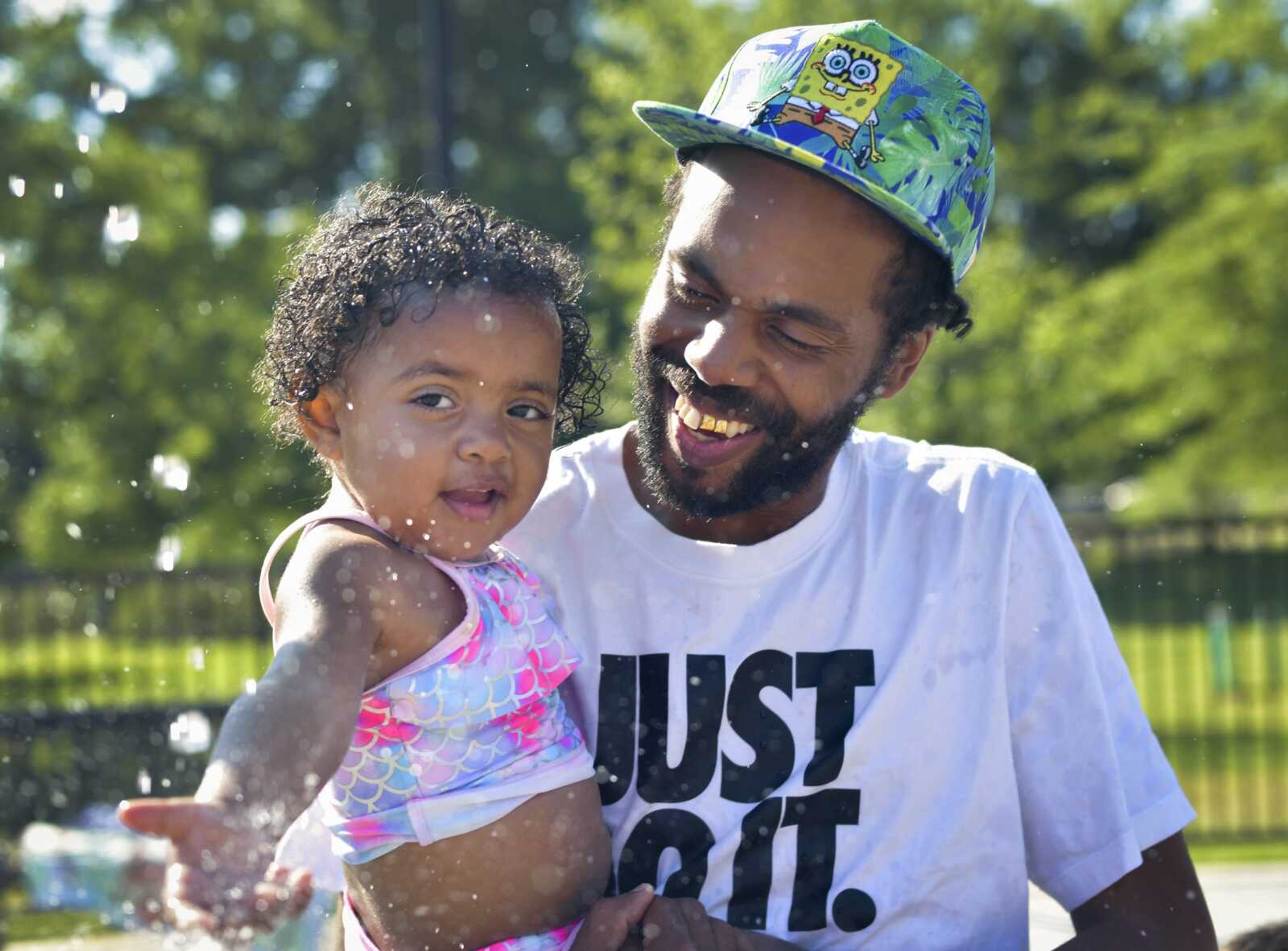 Ryan Mosley of Cape Girardeau laughs as his 2-year-old daughter Neibi cautiously reaches her hand into a stream of water Wednesday, June 17, 2020, at the Capaha Park Splash Pad in Cape Girardeau.