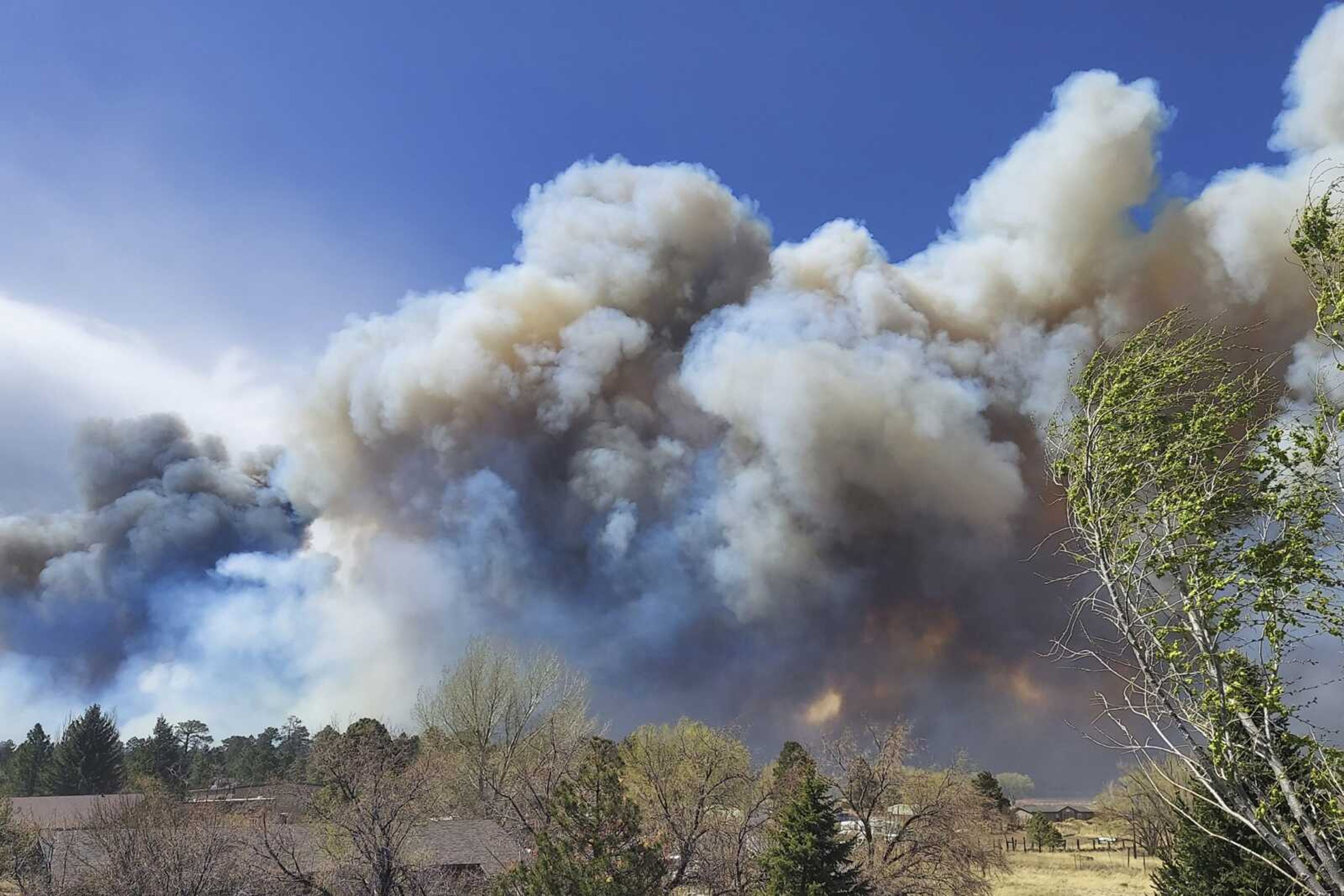 Smoke from a wind-whipped wildfire rises above neighborhoods Tuesday on the outskirts of Flagstaff, Arizona. Homes on the outskirts of Flagstaff were being evacuated Tuesday as high winds whipped a wildfire, shut down a major highway and grounded firefighting aircraft.