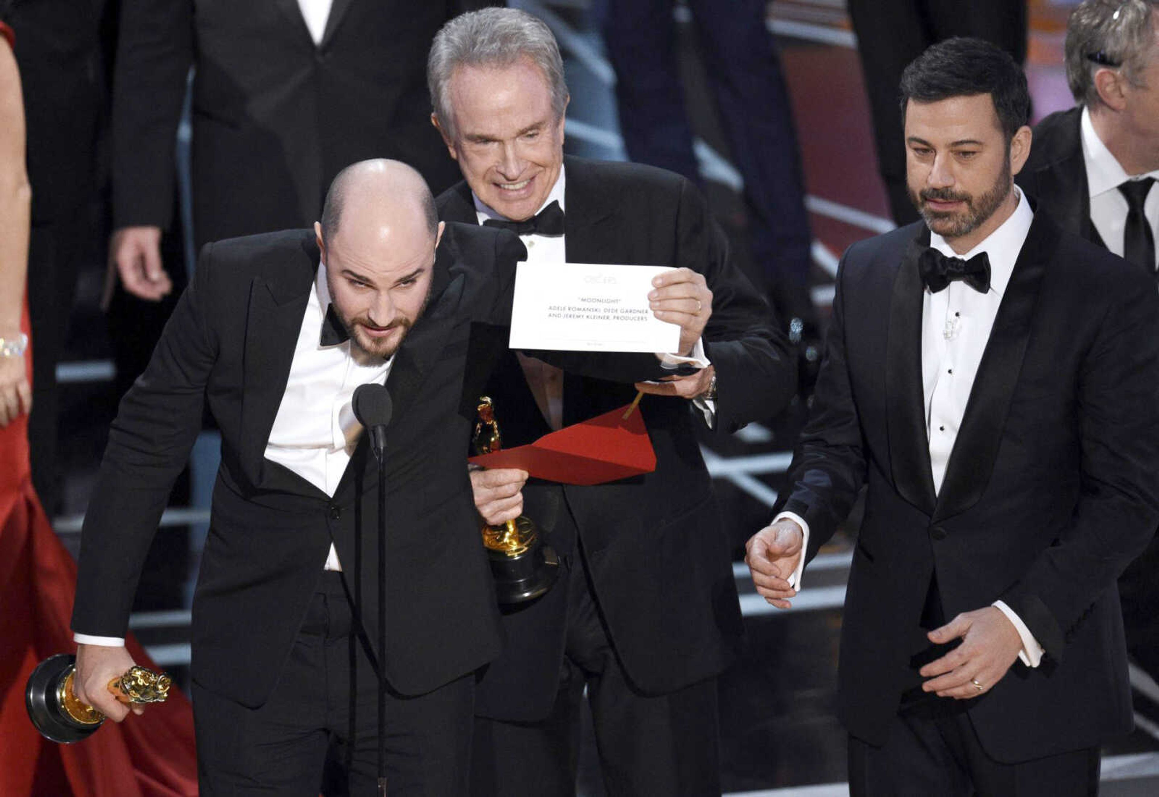 Jordan Horowitz, producer of "La La Land," left, shows the envelope revealing "Moonlight" as the true winner of best picture at the Oscars in Los Angeles as presenter Warren Beatty and host Jimmy Kimmel, right, look on Feb. 26.