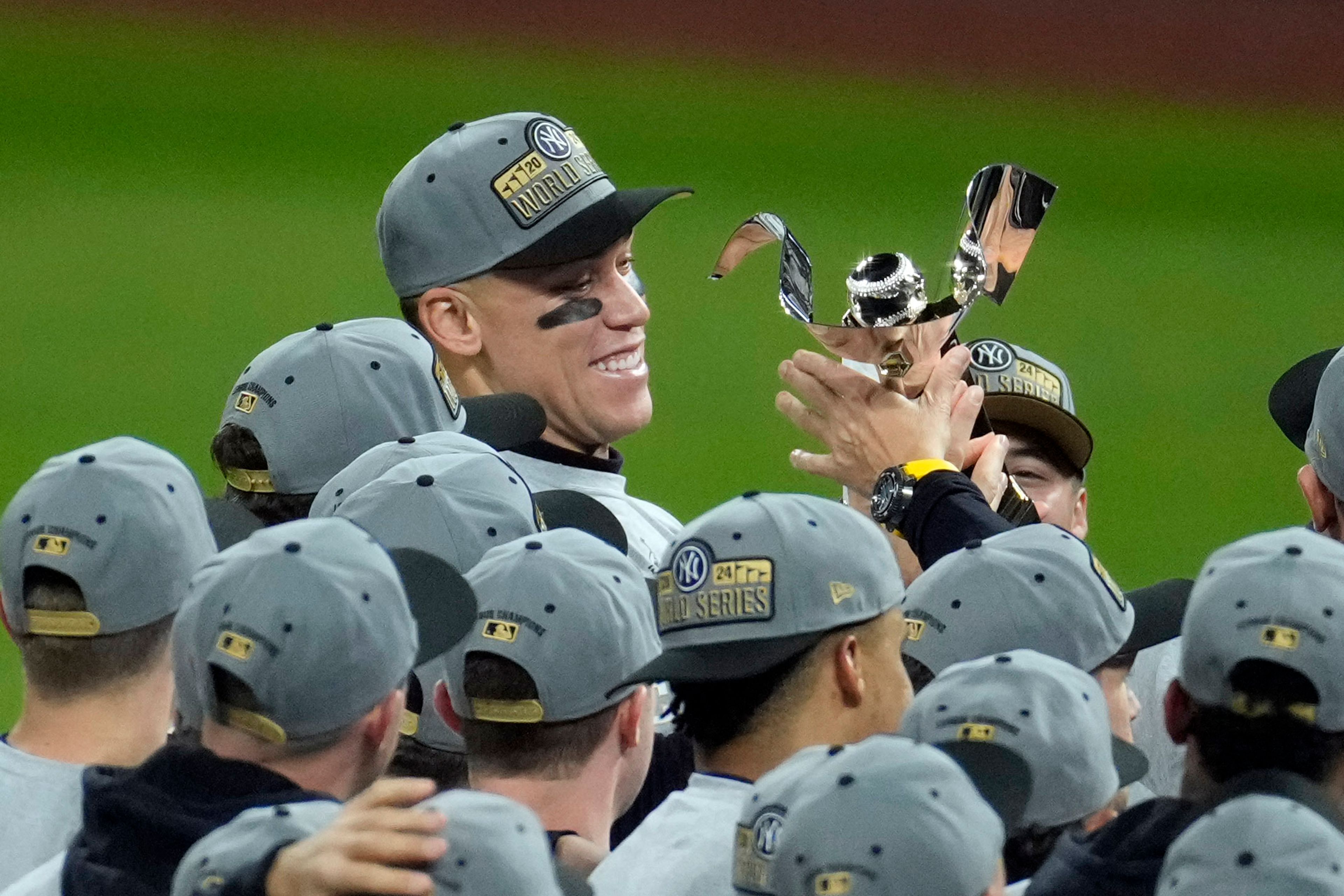 New York Yankees' Aaron Judge holds the American League Championship trophy after Game 5 of the baseball AL Championship Series against the Cleveland Guardians Sunday, Oct. 20, 2024, in Cleveland. The Yankees won 5-2 to advance to the World Series. (AP Photo/Jeff Roberson)