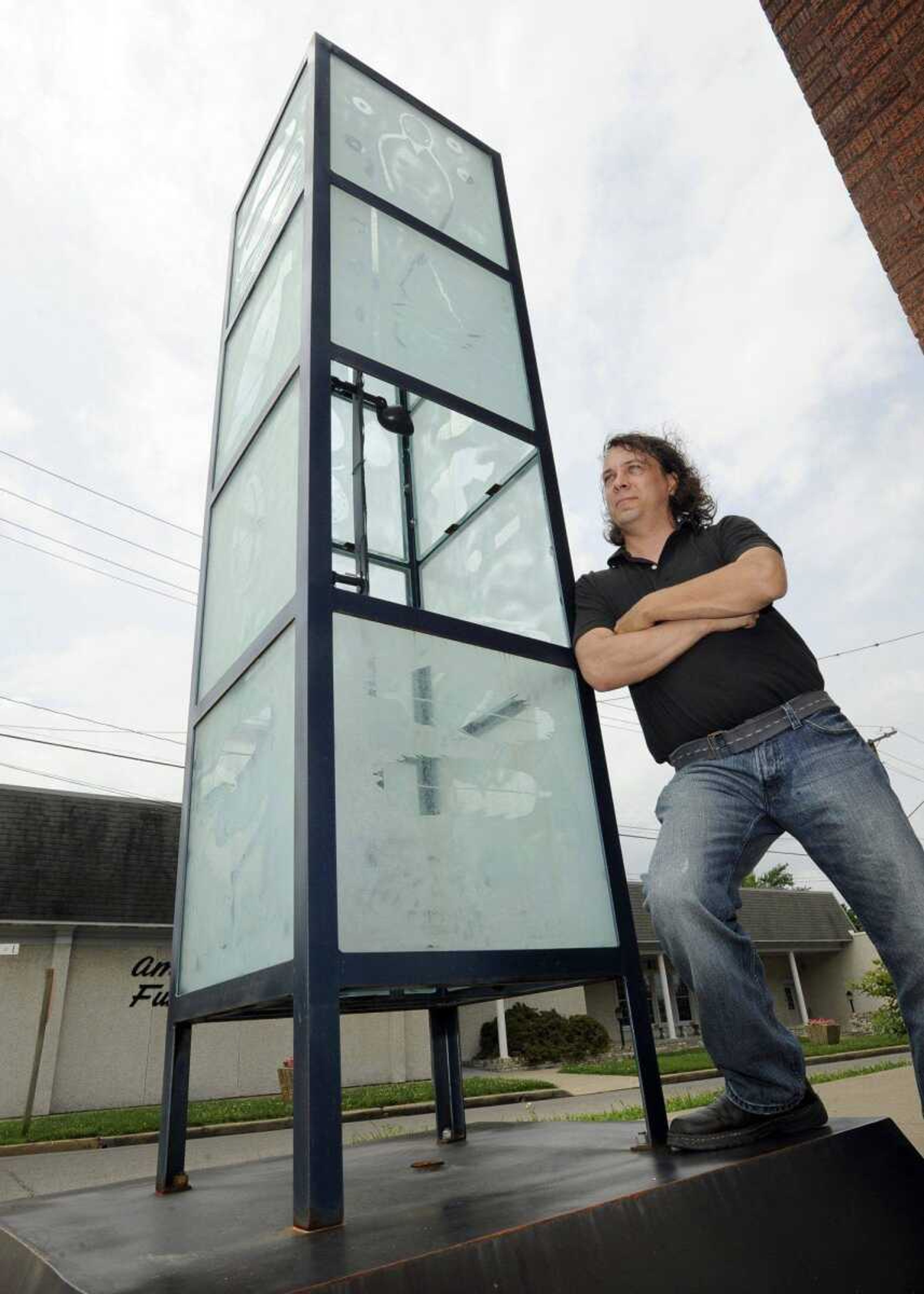 Paul Schock stands next to his sculpture with a panel missing due to vandalism. (Fred Lynch)