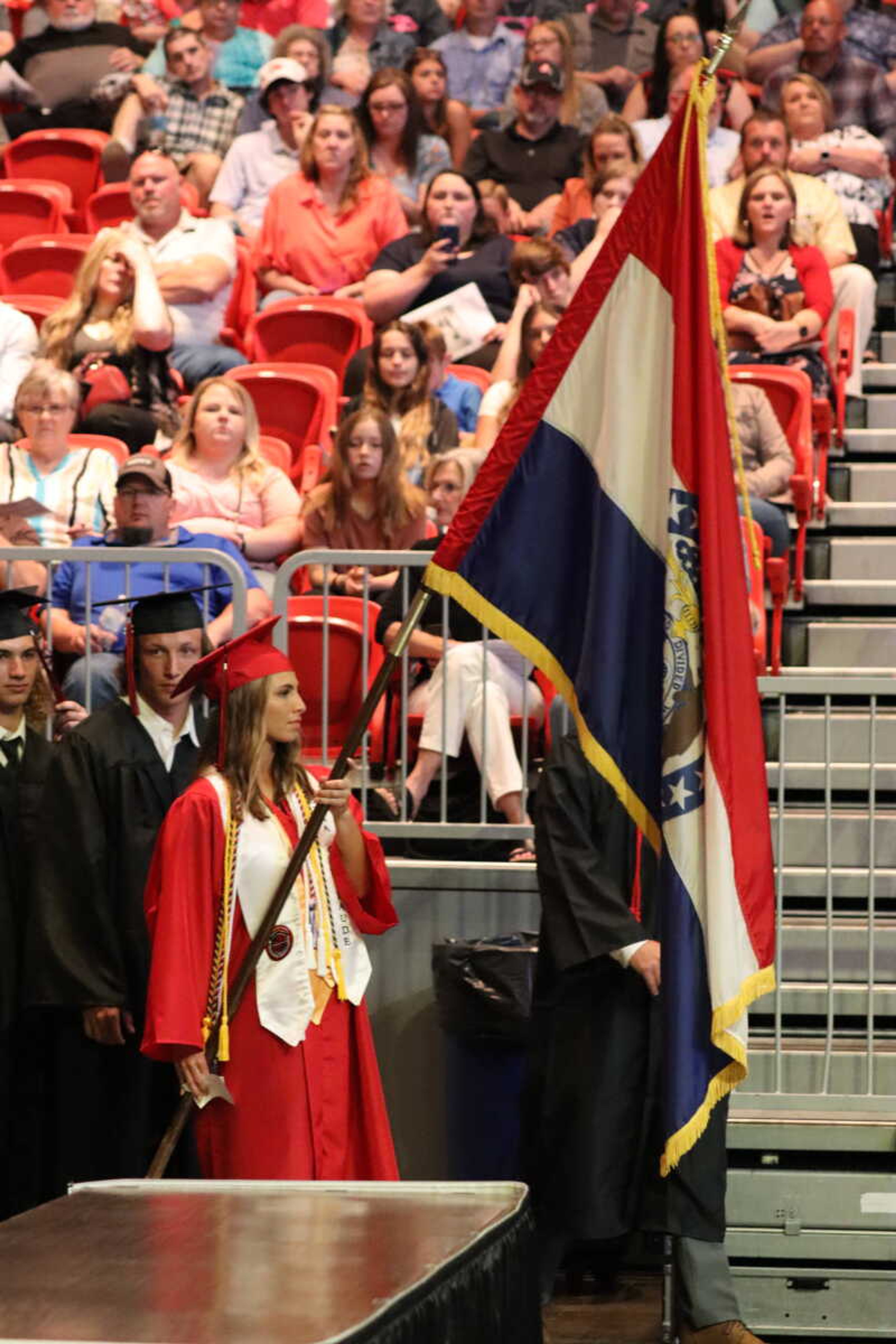 Senior Class President Emma Shields carrying the flag while leading the graduating class to their seats.