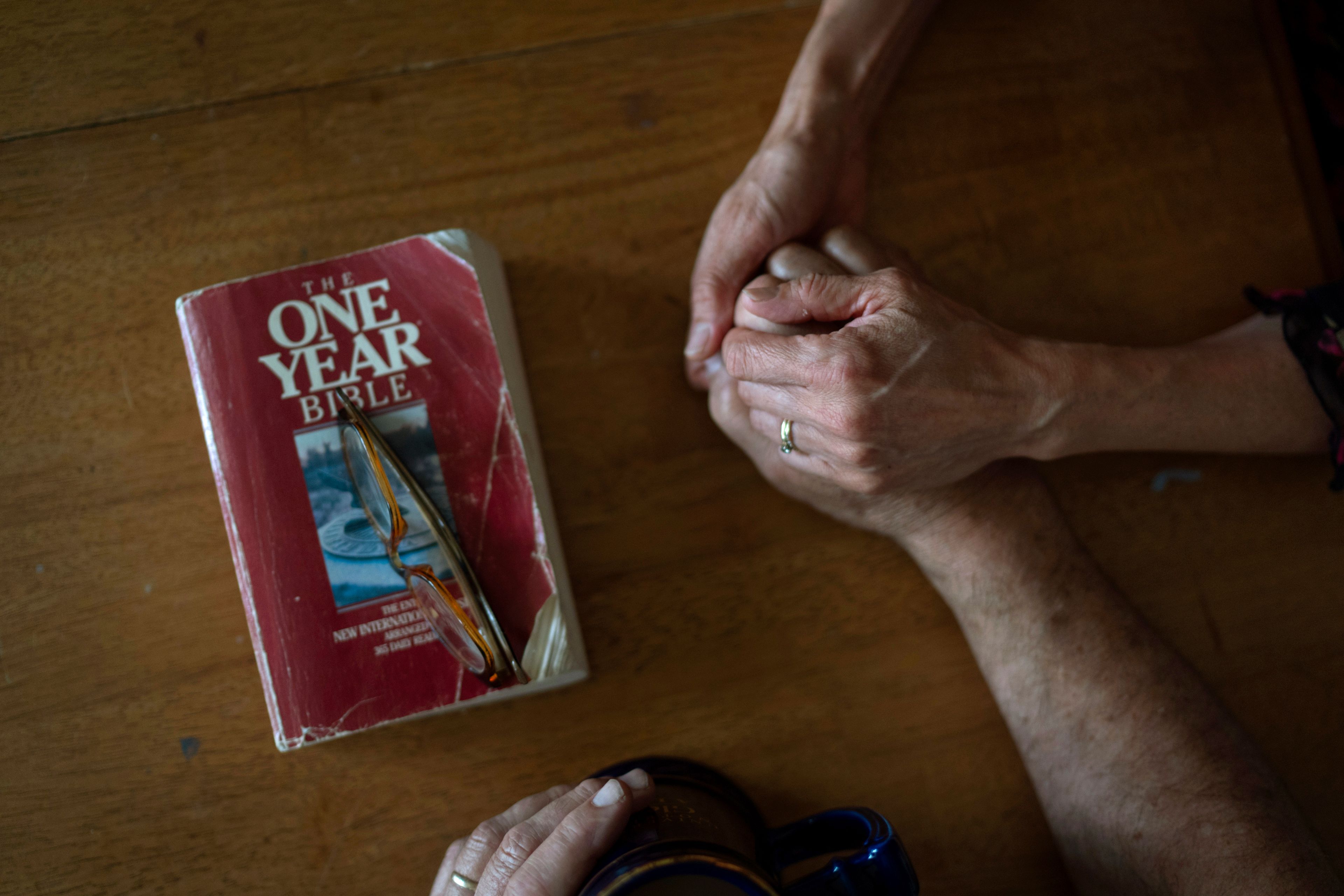 Lesley, right, and Matt Dzik, hold hands as they pray after reading the Bible, Sunday, Sept. 22, 2024, at their home in Champaign, Ill. The couple attend church regularly and when they pray, they hold each other. (AP Photo/David Goldman)