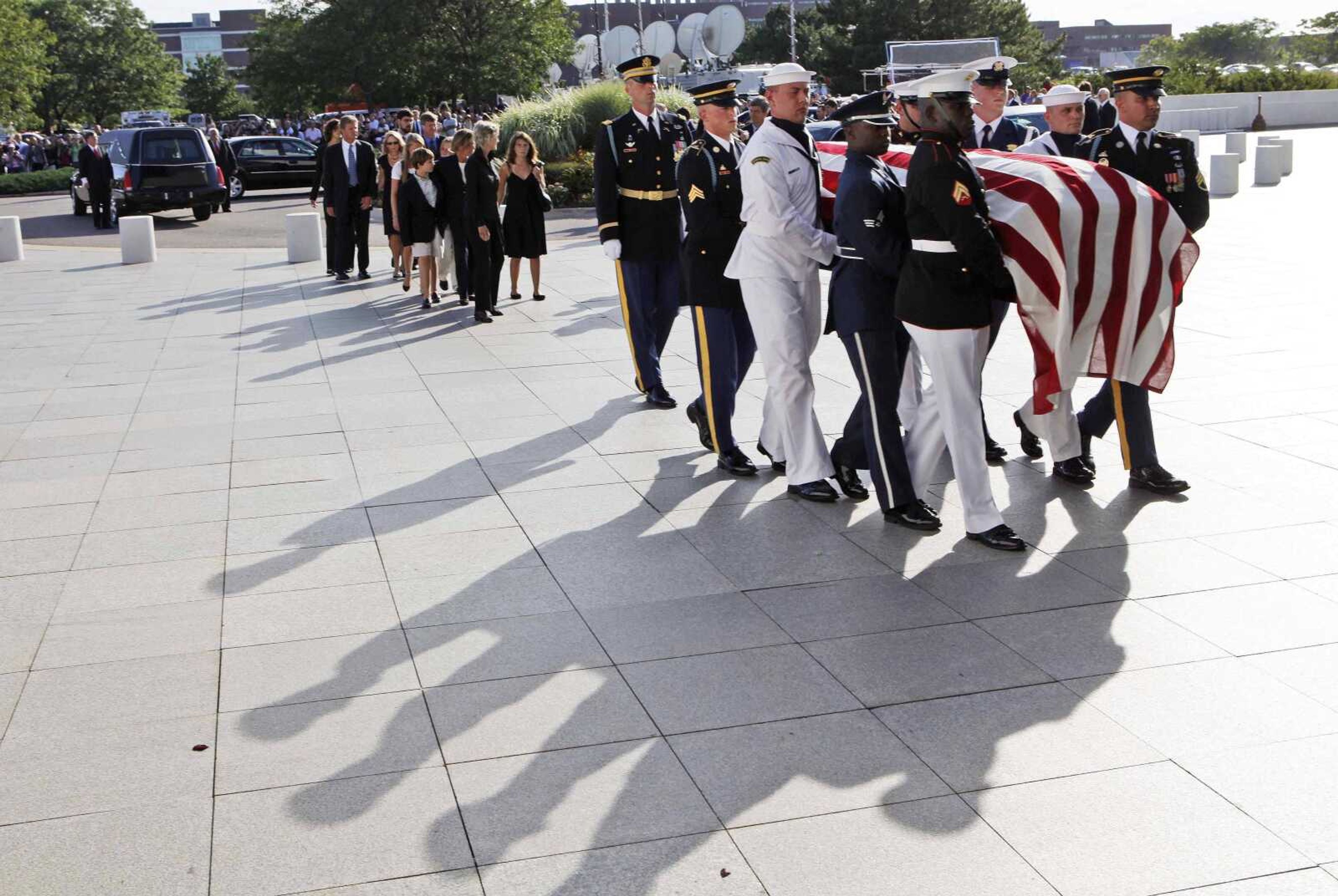 Family members follow an honor guard carrying the casket of Sen. Edward Kennedy as it arrives Thursday at the John F. Kennedy Presidential Library in Boston. (Charles Dharapak ~ Associated Press)