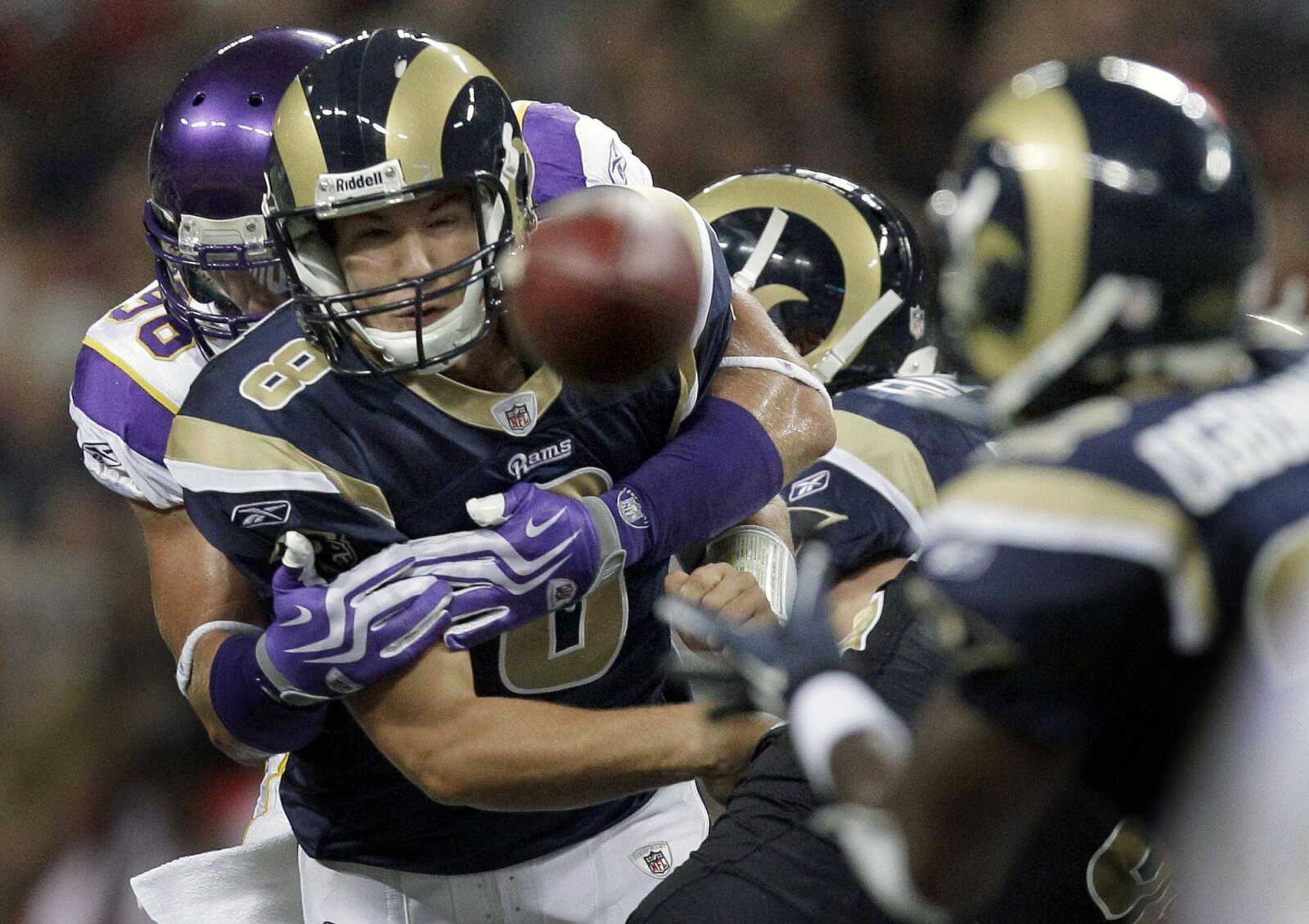 St. Louis Rams quarterback Sam Bradford throws a pass to Rams running back Chris Ogbonnaya, right, while being hit by Minnesota Vikings defensive tackle Letroy Guion, left, during the second quarter of a preseason NFL football game Saturday, Aug. 14, 2010, in St Louis. (AP Photo/Jeff Roberson)