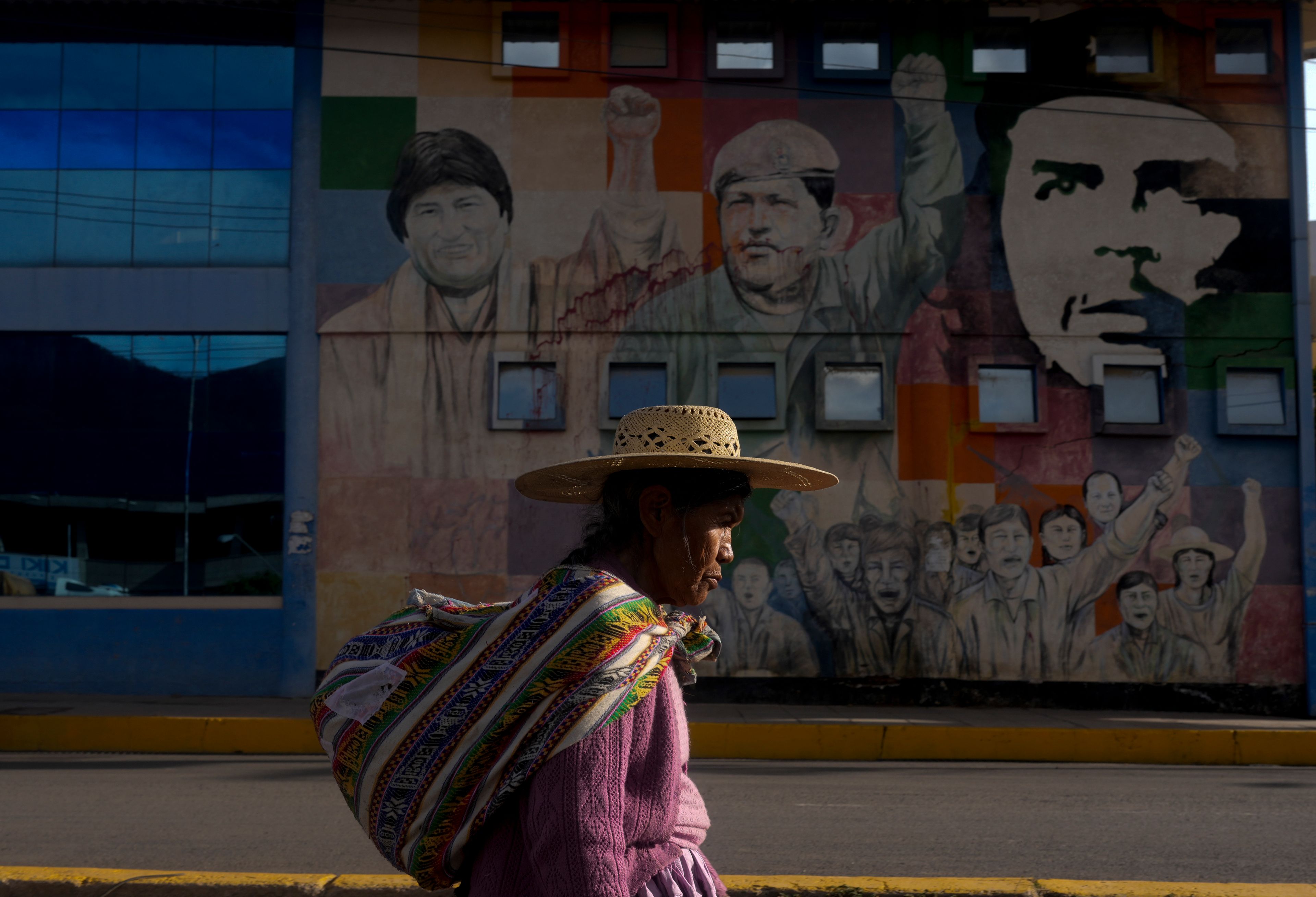 FILE - A woman walks past a mural featuring socialist leaders, from left; former Bolivian President Evo Morales, late Venezuelan President Hugo Chavez and revolutionary Ernesto "Che: Guevara, at the bus terminal in Sacaba, Bolivia, Nov. 20, 2024. (AP Photo/Juan Karita, File)