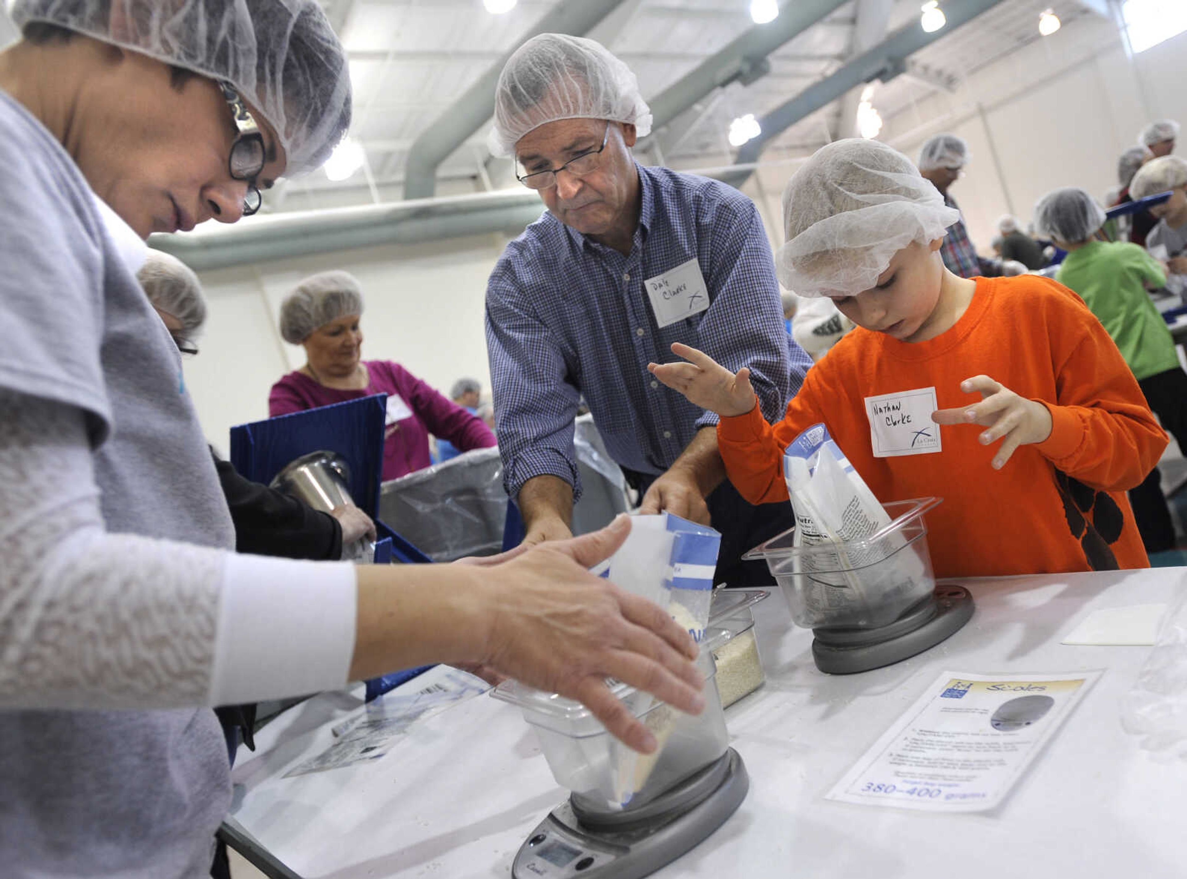 Donna Asendorf, left, checks the weight of the MannaPack Rice meals with Dale Clarke and Nathan Clarke. Each meal must weigh 380 to 400 grams.