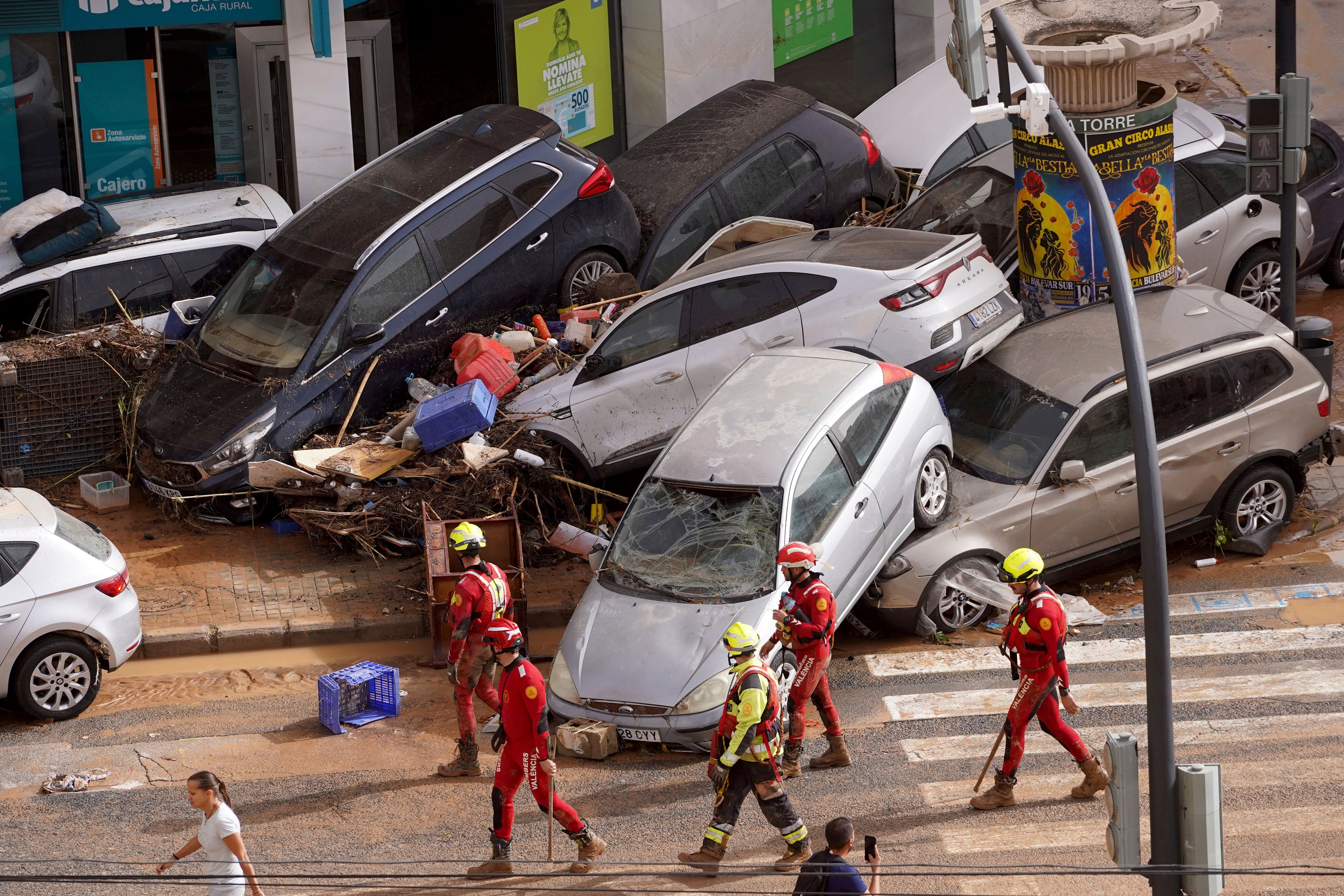 Emergency crew members walk past cars piled up after being swept away by floods in Valencia, Spain, Wednesday, Oct. 30, 2024. (AP Photo/Alberto Saiz)