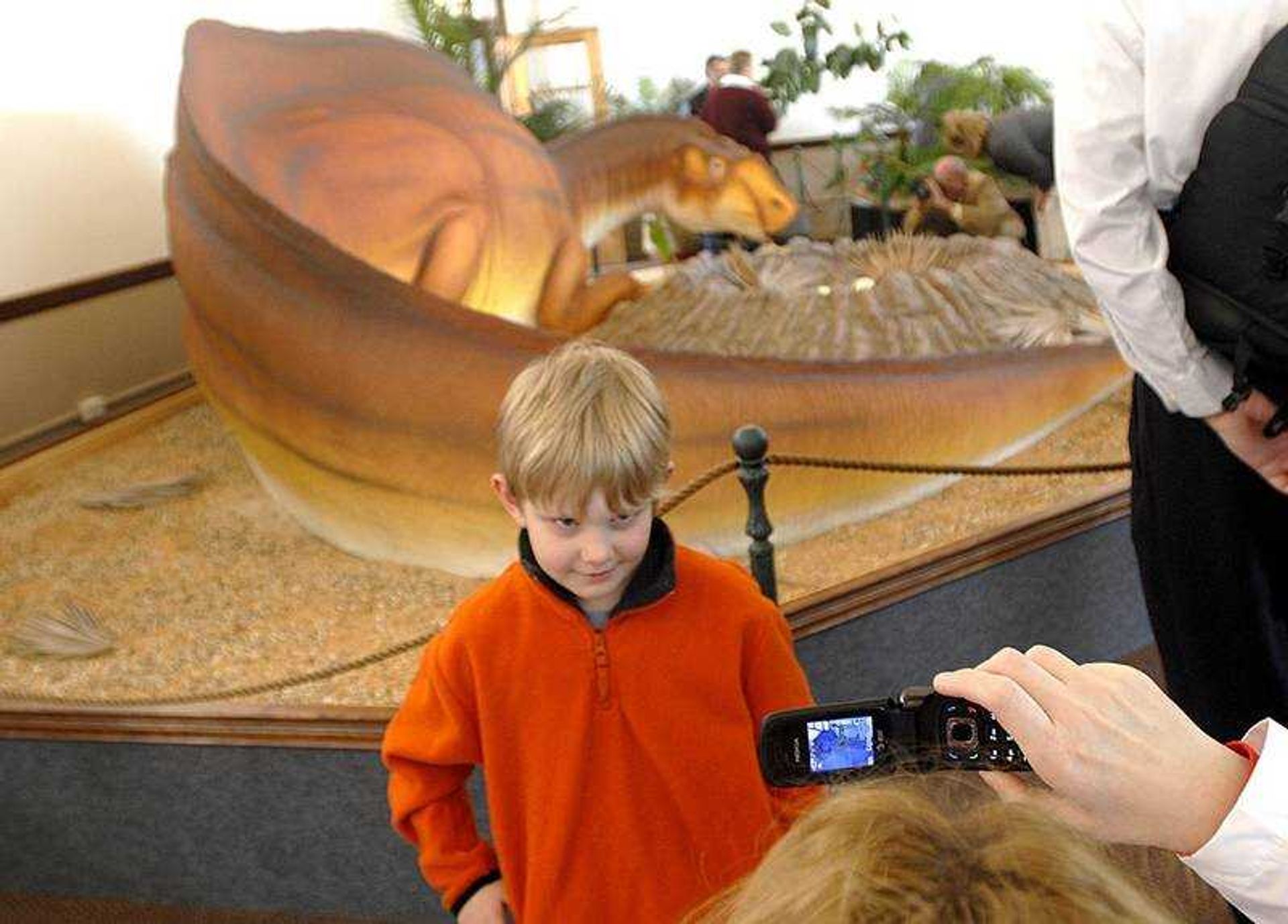 Karry Felty used a cell phone to take a photograph of her son, Reece, 6, next to the Missouri Dinosaur replica Friday at the Bollinger County Museum of Natural History.