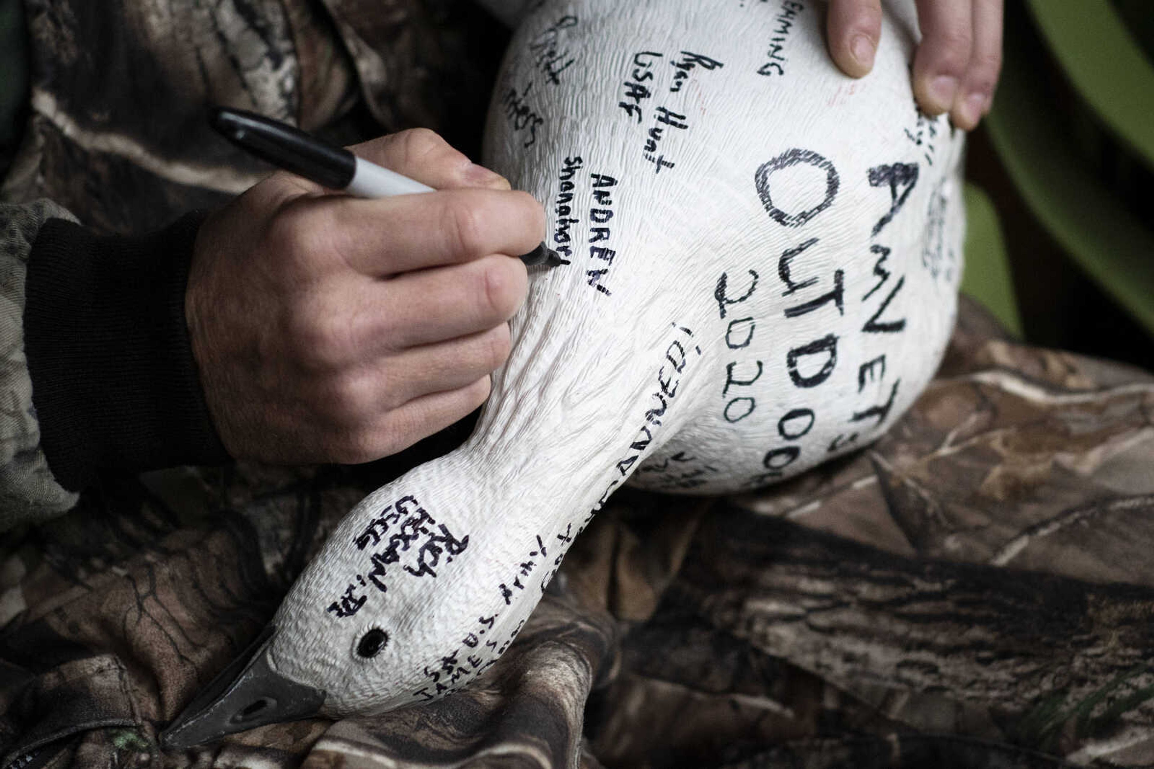 Active duty Air Force member Andrew Shanahorn, originally of Columbus, Ohio, and now at Scott Air Force Base, signs a decoy featuring the names of other veterans during a snow geese hunt with AM Vets Outdoors on Saturday, March 14, 2020, in Ware, Illinois.