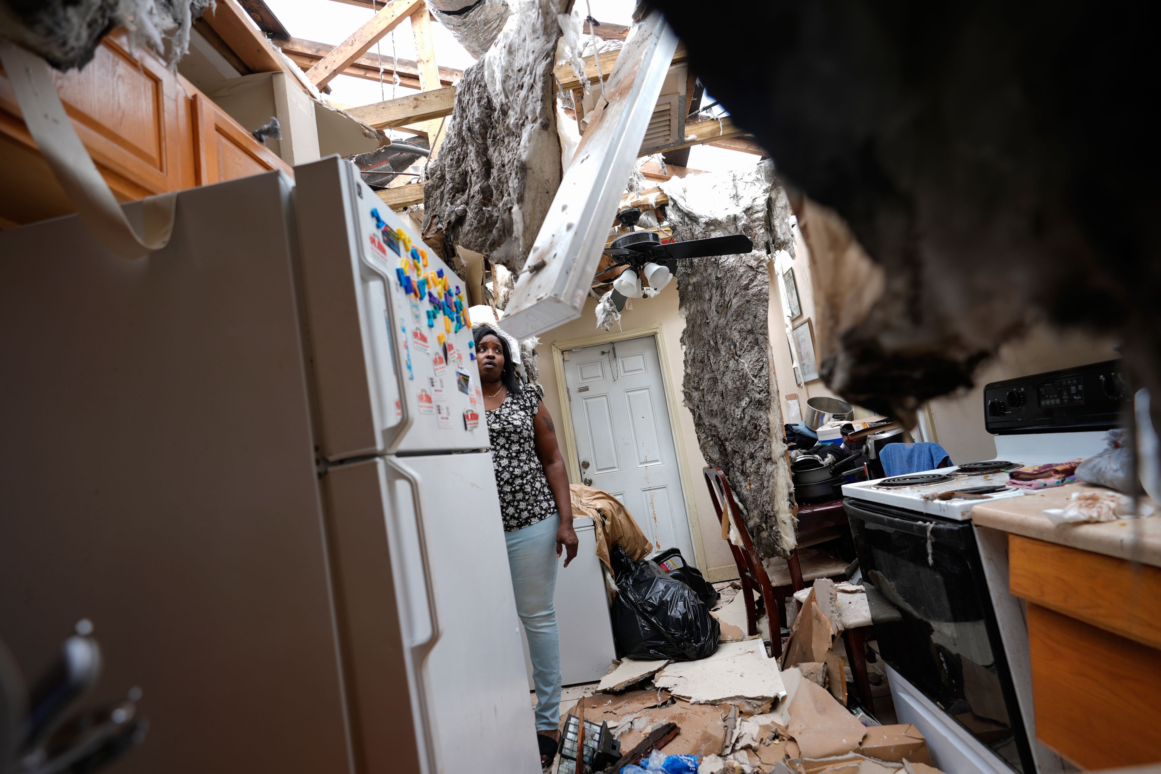 Natasha Ducre surveys the kitchen of her devastated home, which lost most of its roof during the passage of Hurricane Milton, in Palmetto, Fla., Thursday, Oct. 10, 2024. Ducre, her husband, three children, and two grandkids rode out the storm in a government shelter and returned to find their home unlivable and much of their furniture and belongings destroyed by rainwater. (AP Photo/Rebecca Blackwell)