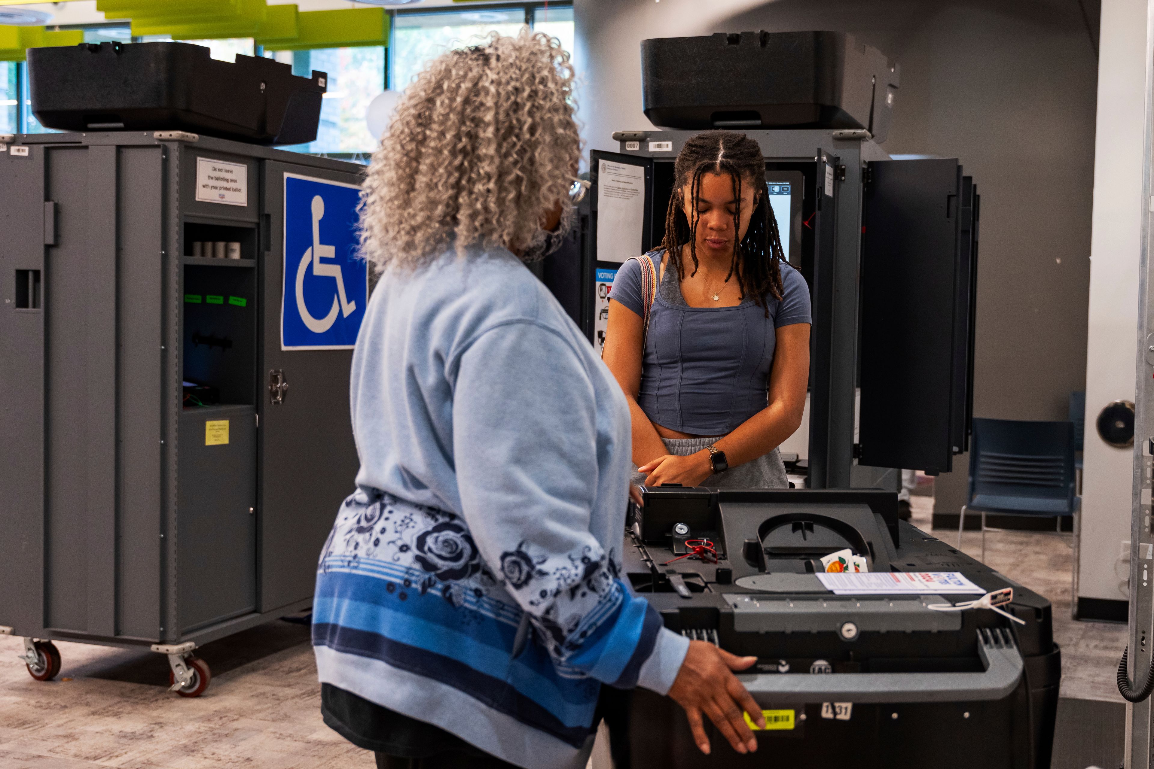 CORRECTS TO CAST BALLOT - A woman receives instructions from a poll worker on how to properly cast her ballot receipt at the polling station, Thursday, Oct. 31, 2024, in Atlanta. (AP Photo/Jason Allen)