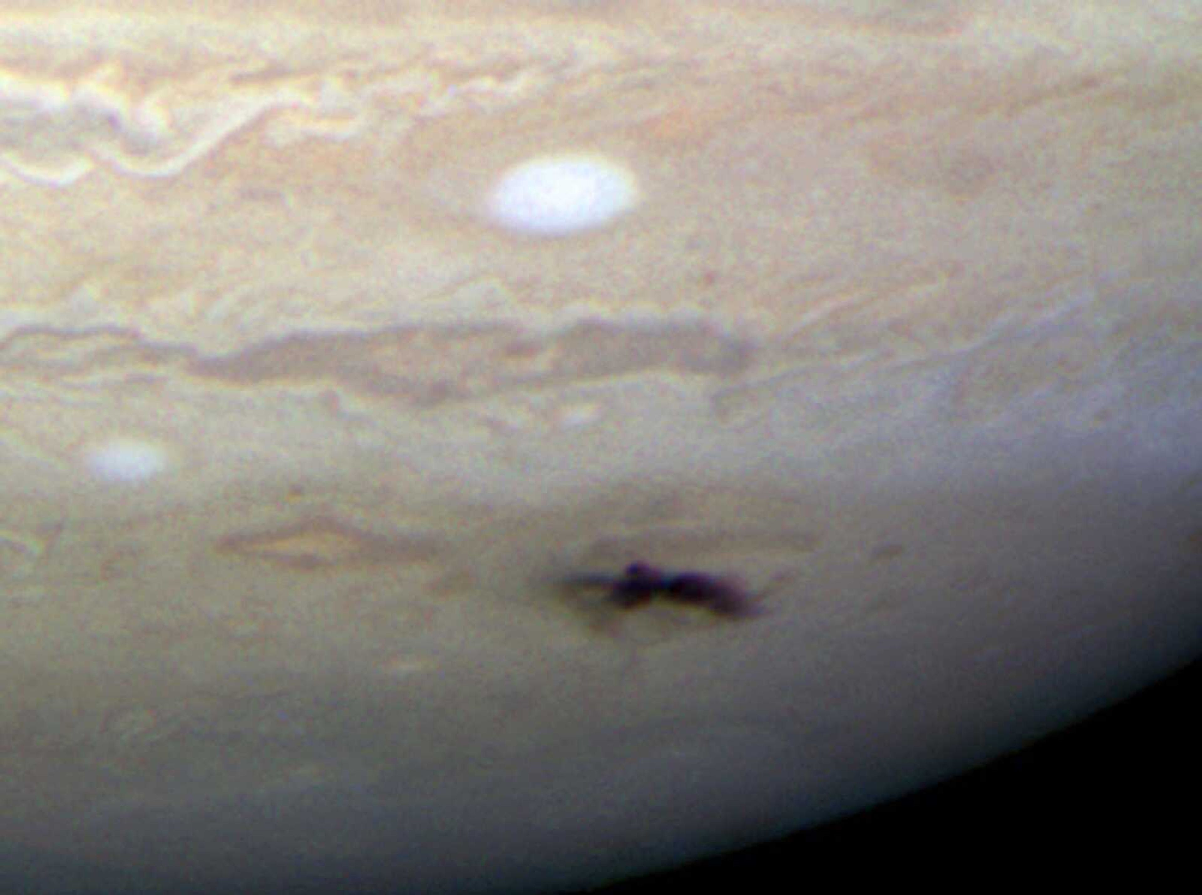 This image shows the sharpest visible-light picture taken of the impact feature (dark spot) and "backsplash" of material from a small object that plunged into Jupiter's atmosphere and disintegrated. (NASA)