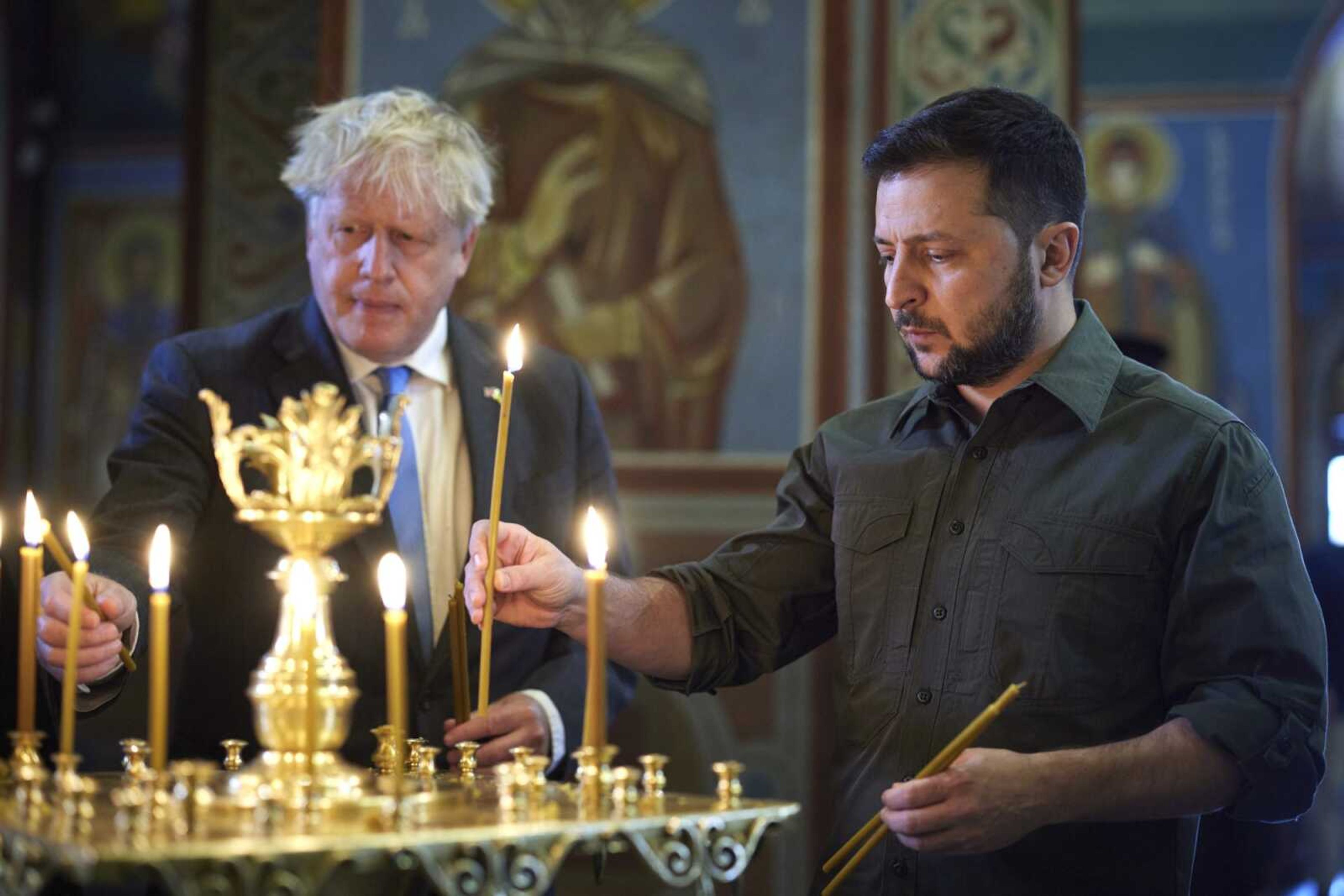 Ukrainian President Volodymyr Zelenskyy, right, and Britain's Prime Minister Boris Johnson light candles Friday as they visit the Mikhailovsky Zlatoverkhy Cathedral (St. Michael's Golden-Domed Cathedral) in Kyiv, Ukraine.