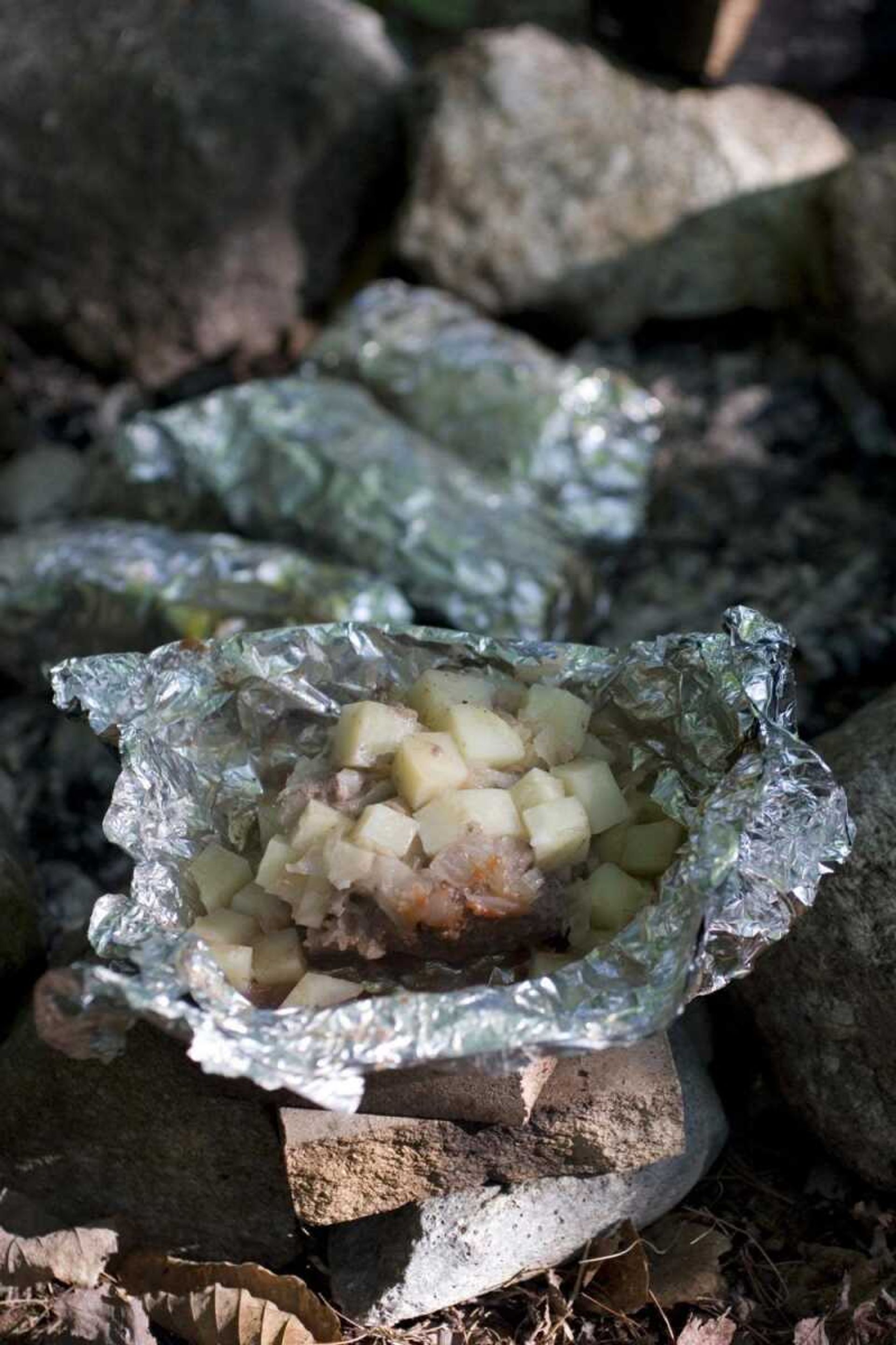 Hungry Hiker Parcels, shown here, can be put together before leaving for a camping trip. After spending about 30 minutes nestled in hot coals, the nearly complete meal in a foil parcel is cooked and ready for eating. (Larry Crowe ~ Associated Press)