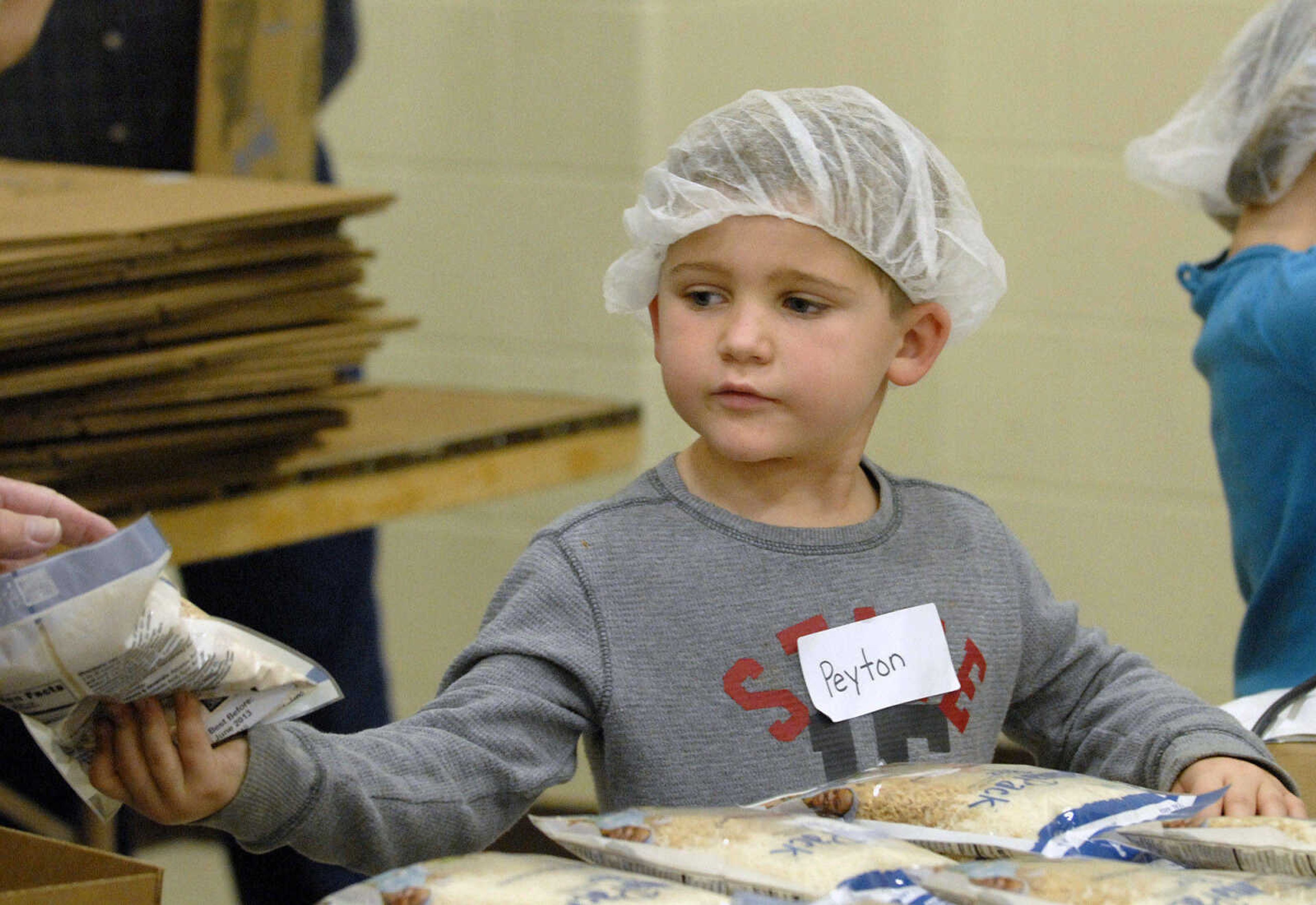 LAURA SIMON ~ lsimon@semissourian.com
Peyton Klund pass down a sealed MannaPack Rice to be boxed Friday night, Dec. 9, 2011 during the Feed My Starving Children Mobilepack event at Shawnee Park center in Cape Girardeau.