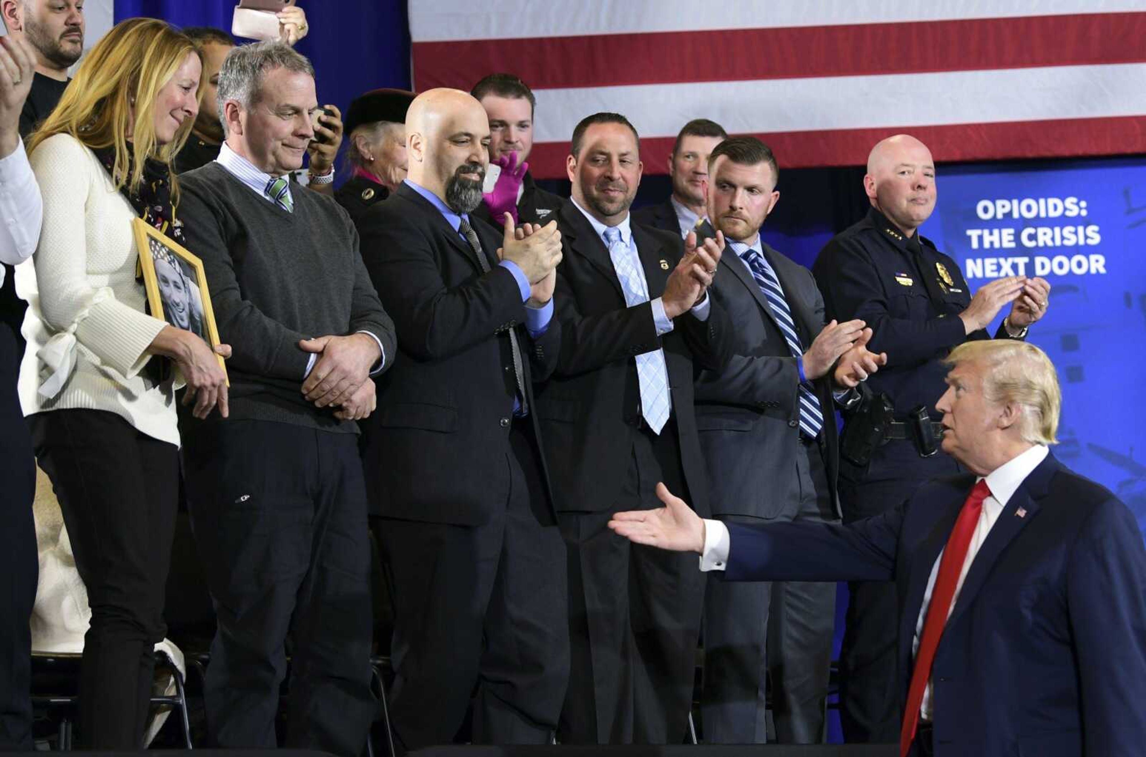 President Donald Trump reaches out to shake the hand of Jeanne Moser during an event Monday at Manchester Community College in Manchester, New Hampshire. Her husband, Jim Moser, stands to her left. Their son Adam died in 2015 of a drug overdose.