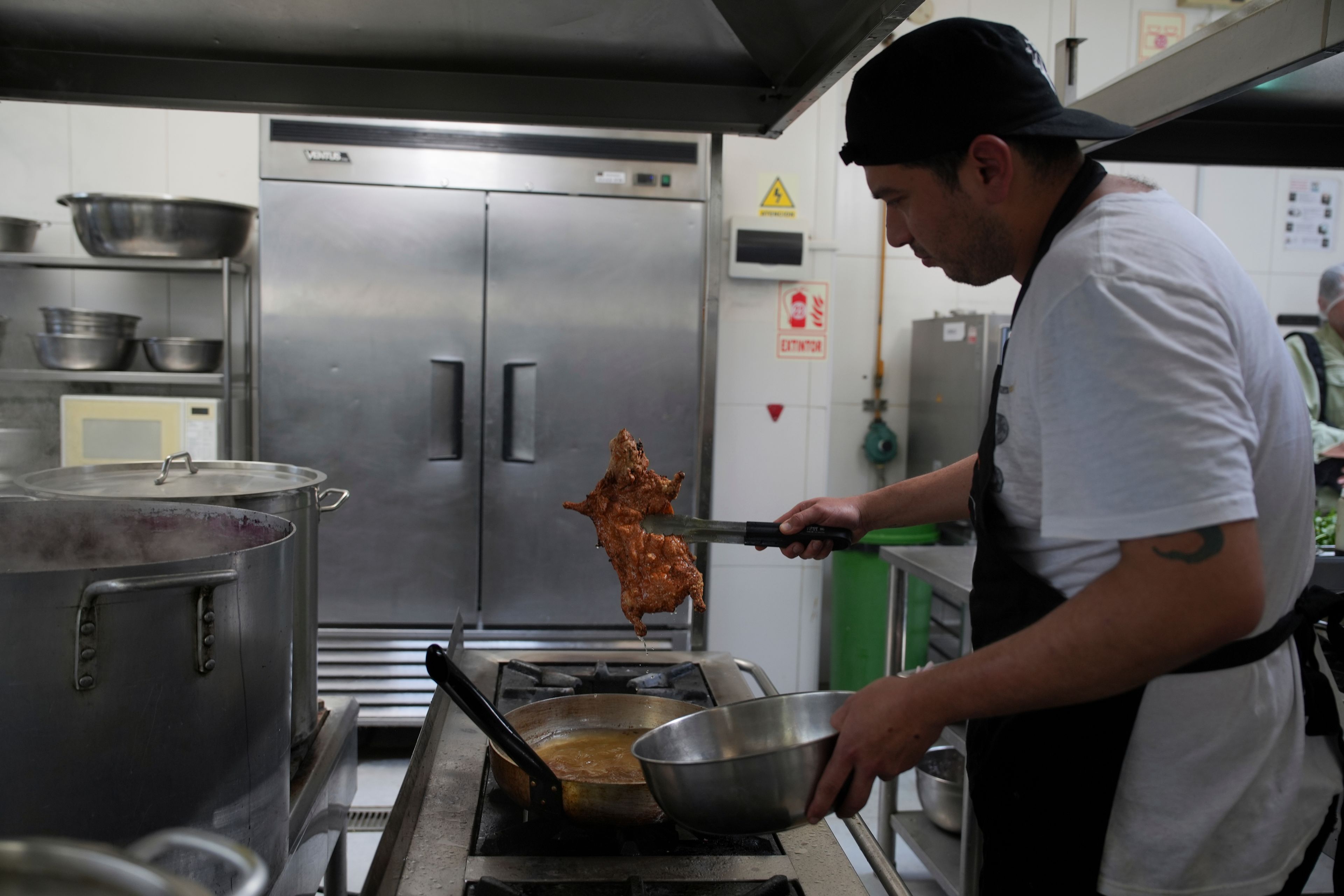 A cook fries guinea pigs at a restaurant in Lima, Peru, Thursday, Oct. 3, 2024. Guinea pigs, locally known as 'cuy,' have been traditionally raised for meat consumption since pre-Inca times. (AP Photo/Guadalupe Pardo)