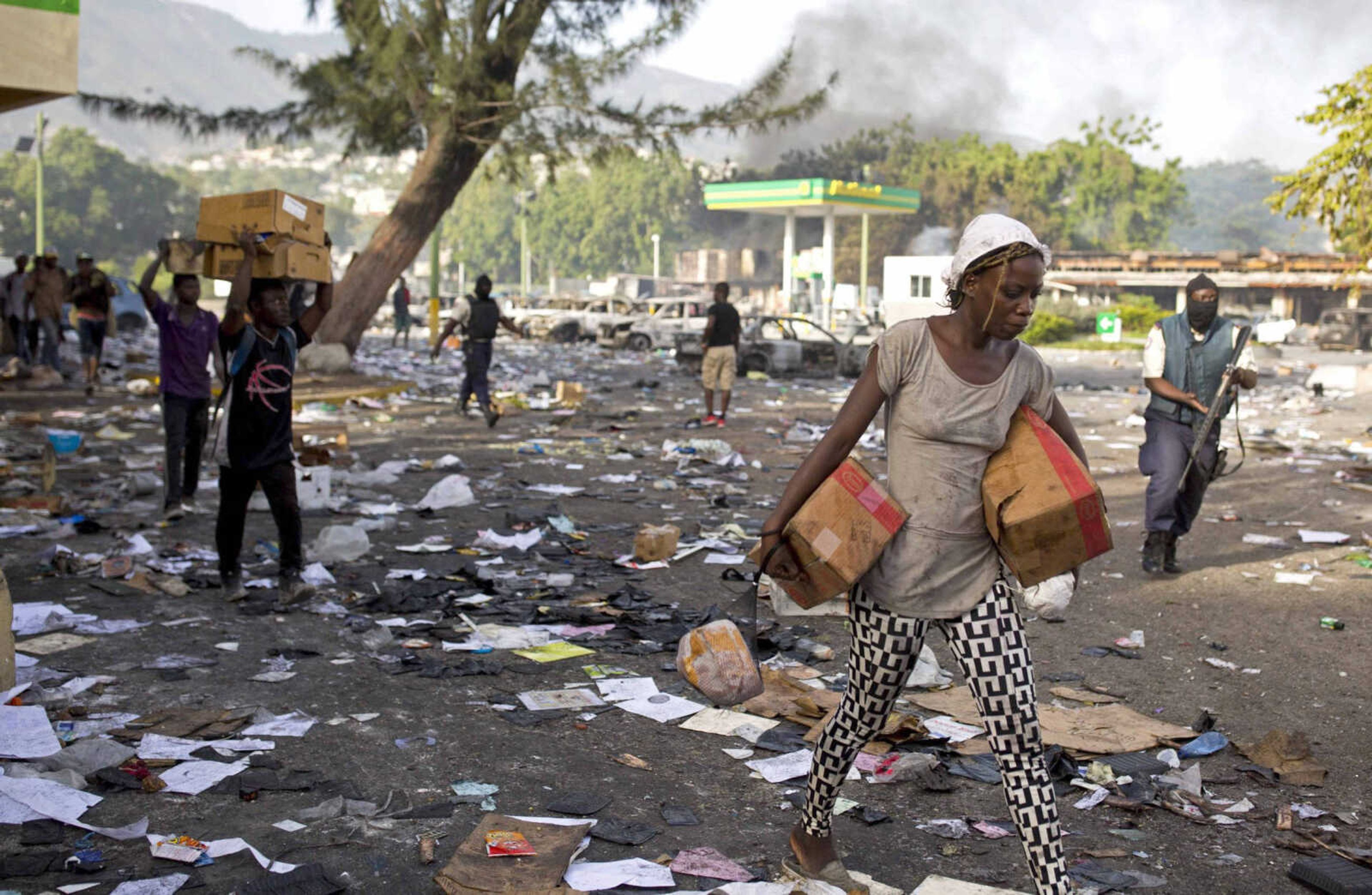 People carry items from a Delimart supermarket complex Sunday that was burned during two days of protests against a planned hike in fuel prices in Port-au-Prince, Haiti.