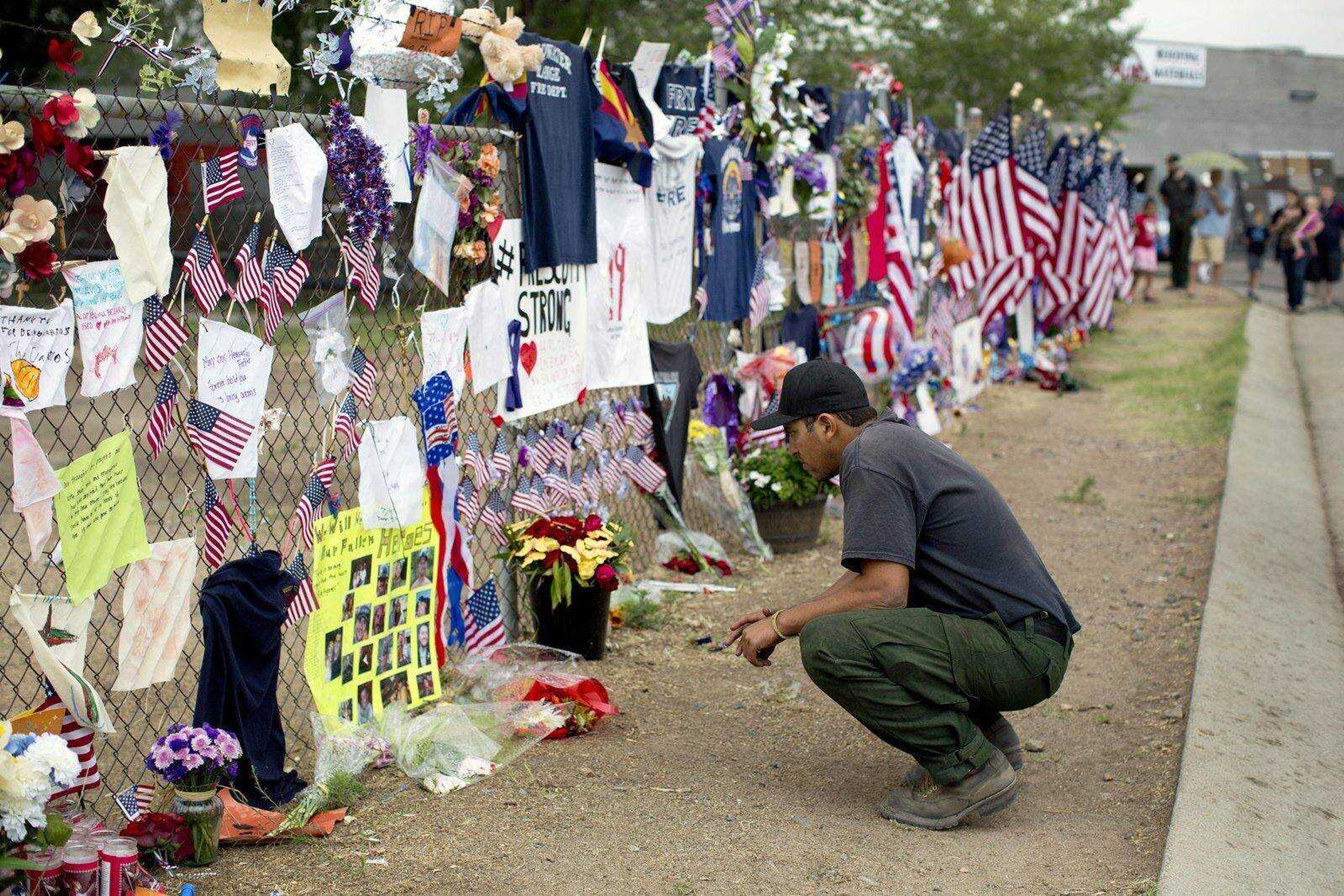 A firefighter from the Valyermo, Calif. fire department examines notes and photos left at a makeshift memorial at the Granite Mountain Hotshot Crew fire station Friday in Prescott, Ariz.  (Julie Jacobson ~ Associated Press)